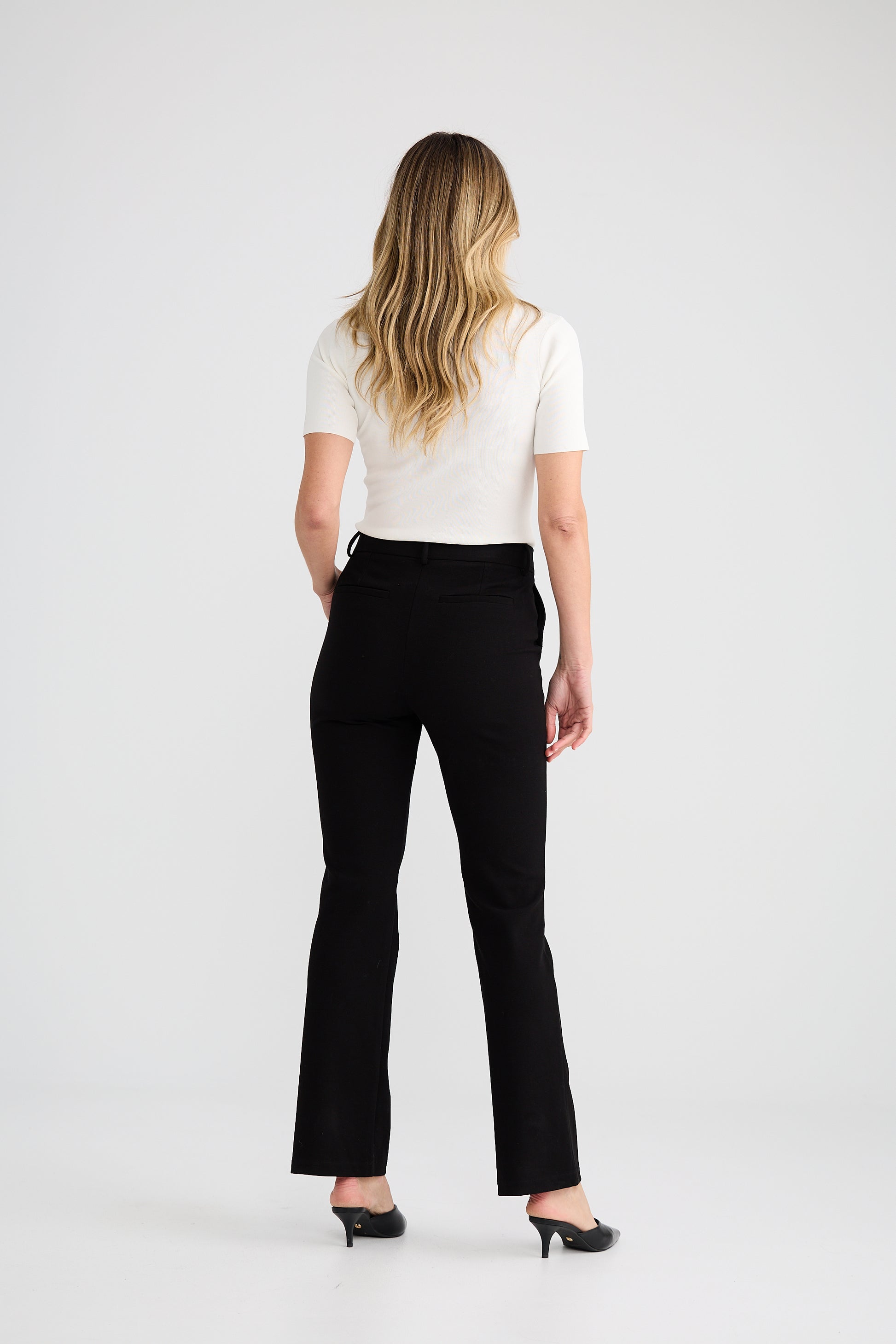 Woman wearing a white top and Brave and True black pants on a white background