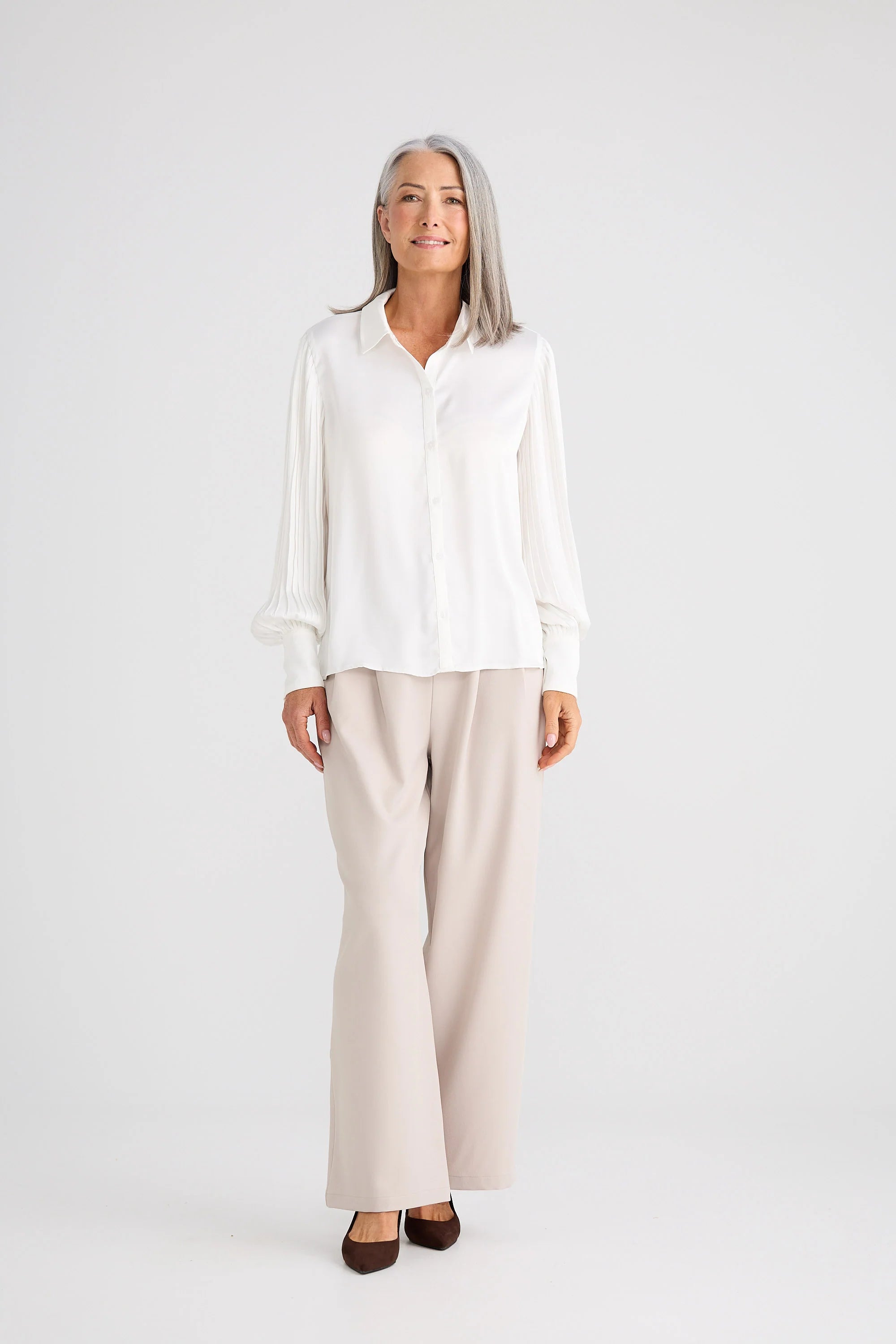 Image of Woman wearing a Brave and True white shirt and beige pants on a white background
