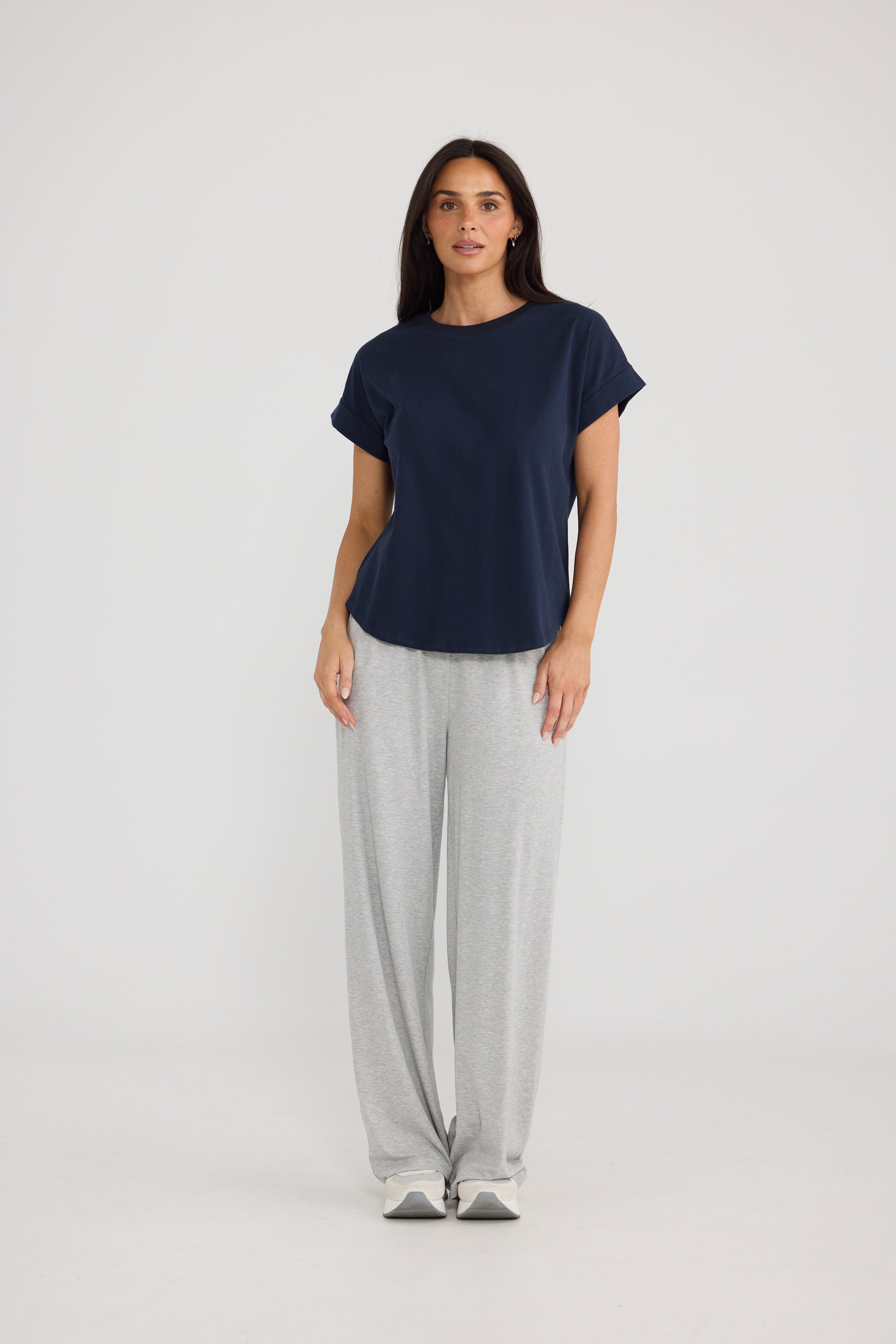 Image of A woman modeling a Brave & True navy blue short-sleeve t-shirt and light gray sweatpants against a plain light gray studio background.