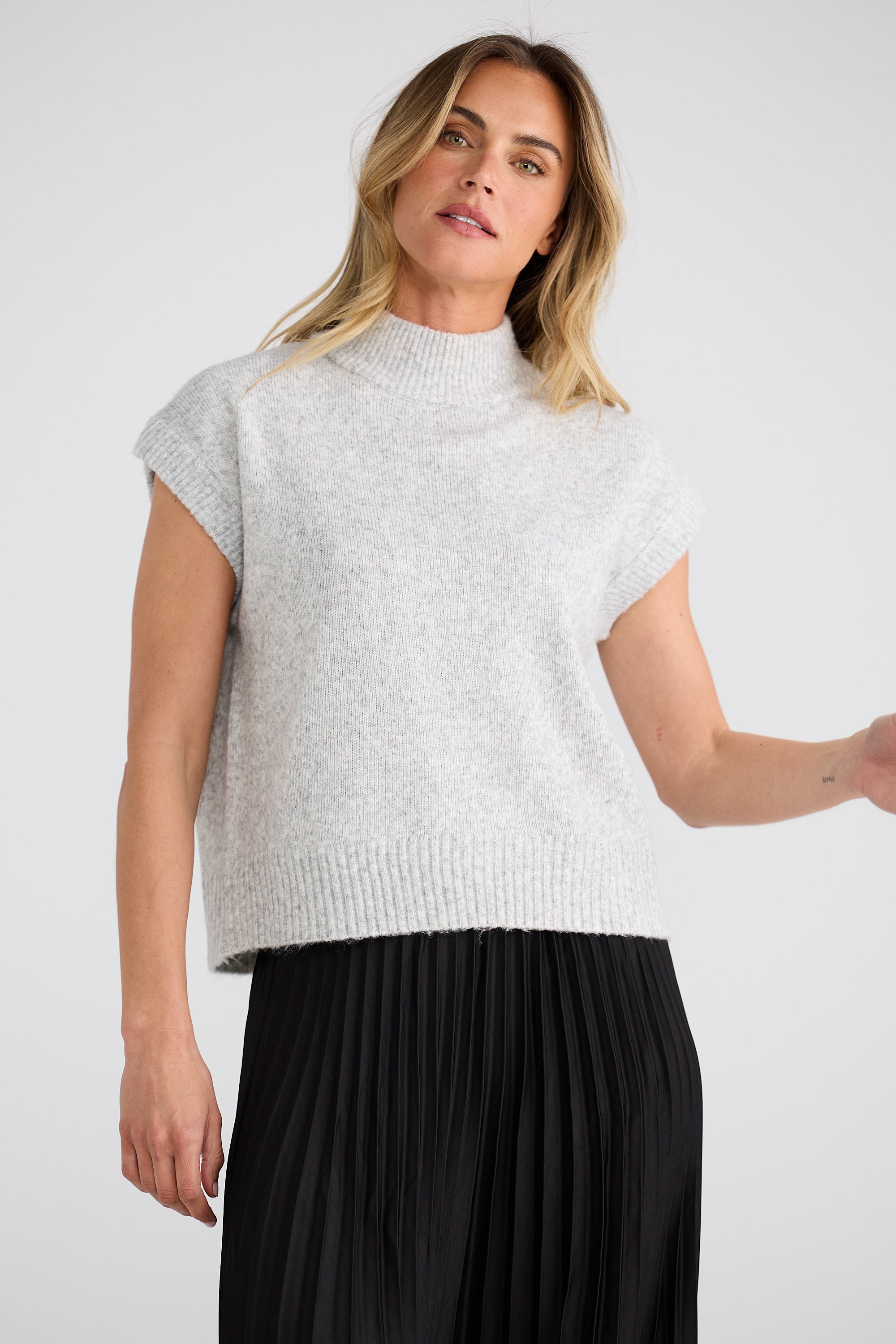 Image of Woman wearing a Brave and True light gray sleeveless sweater and black pants on a white background