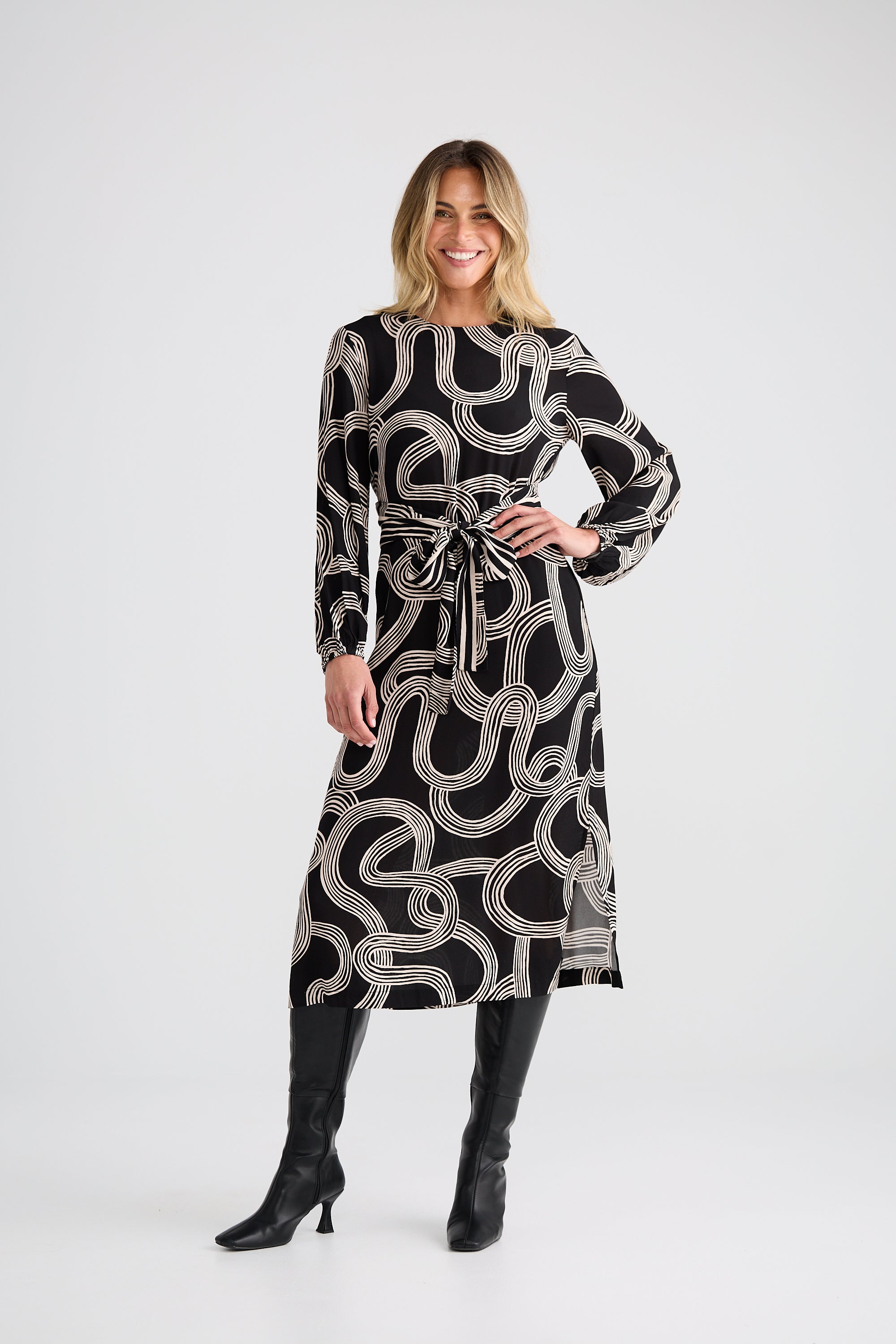 Image of Woman wearing a Brave and True black and white patterned dress with long sleeves on a white background