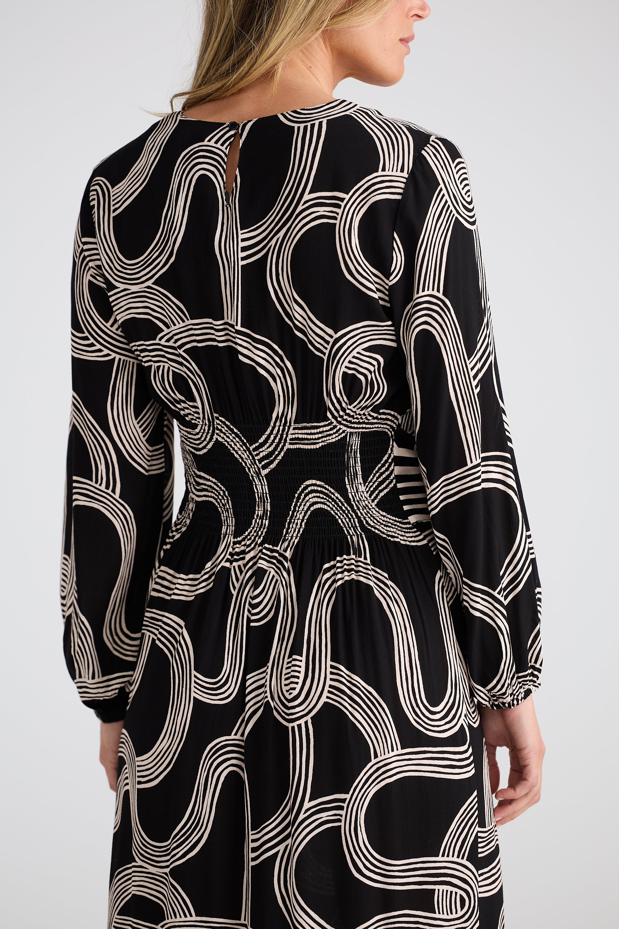 Image of Brave and True black dress with white abstract pattern worn by a woman on a plain background