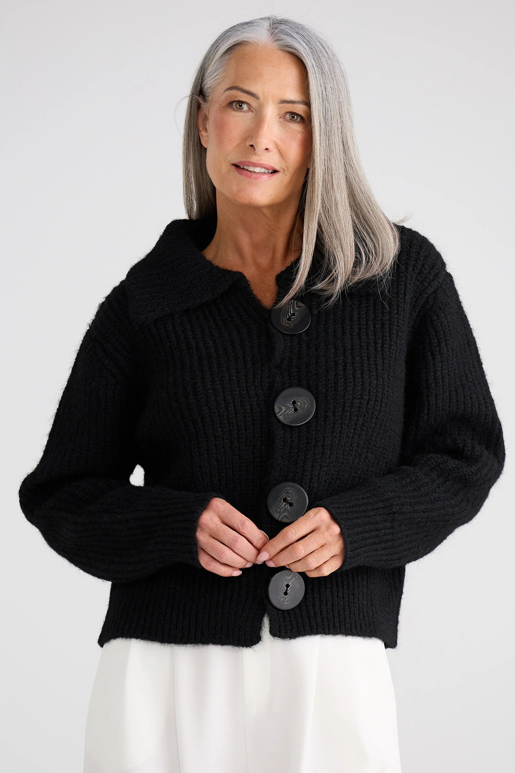 Woman wearing a Brave and True black button-up cardigan against a white background