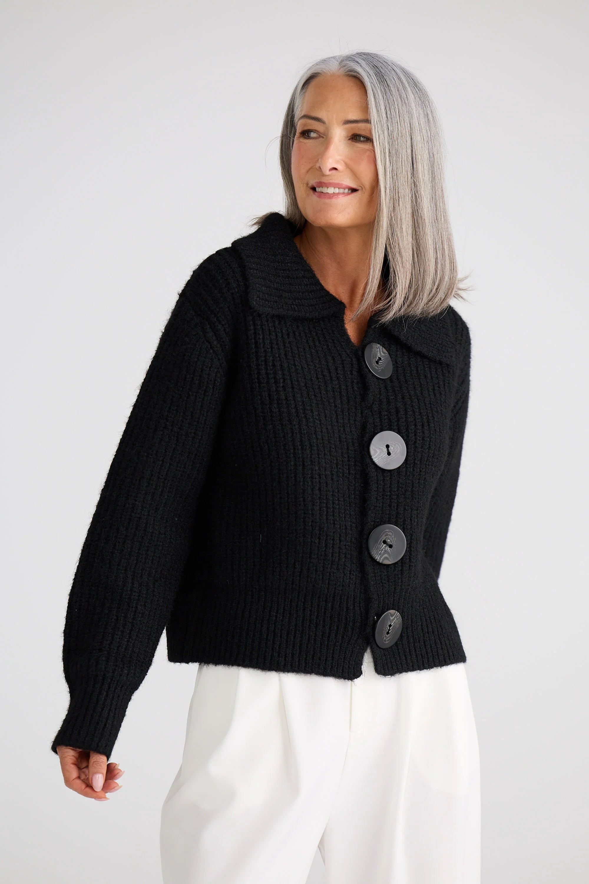Image of Woman wearing a Brave and True black ribbed knit cardigan with buttons on a white background