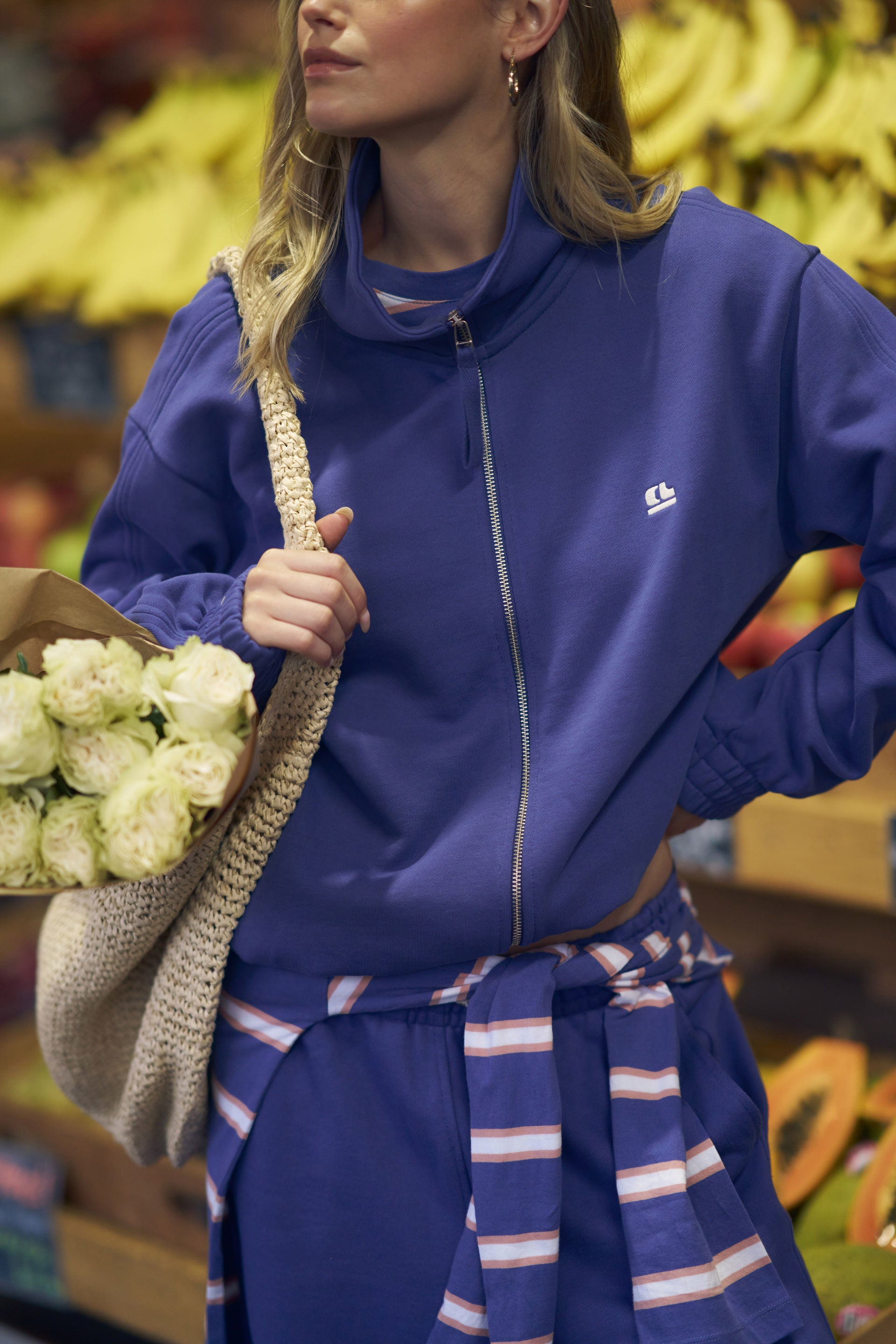 Person wearing a blue outfit holding flowers in a grocery store setting