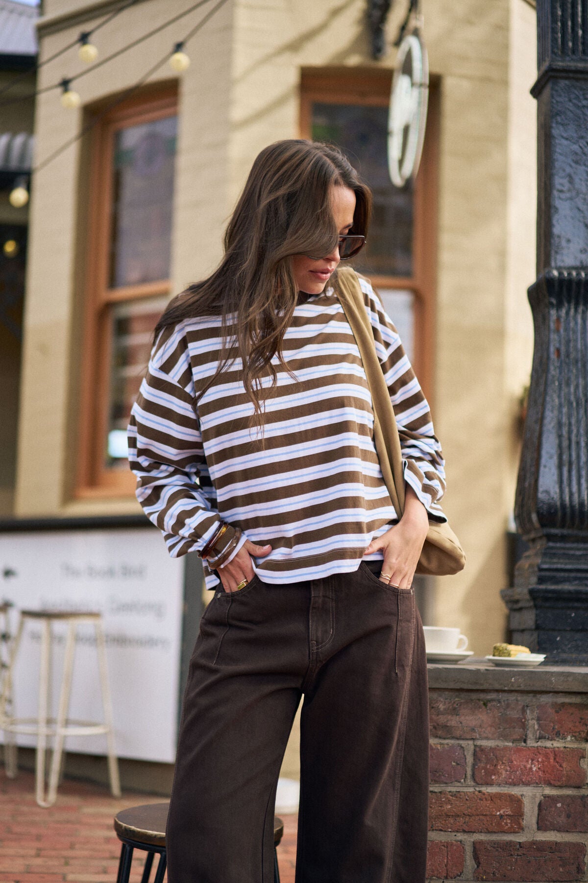 Woman wearing a Ceres Life striped sweater and brown pants standing outdoors.