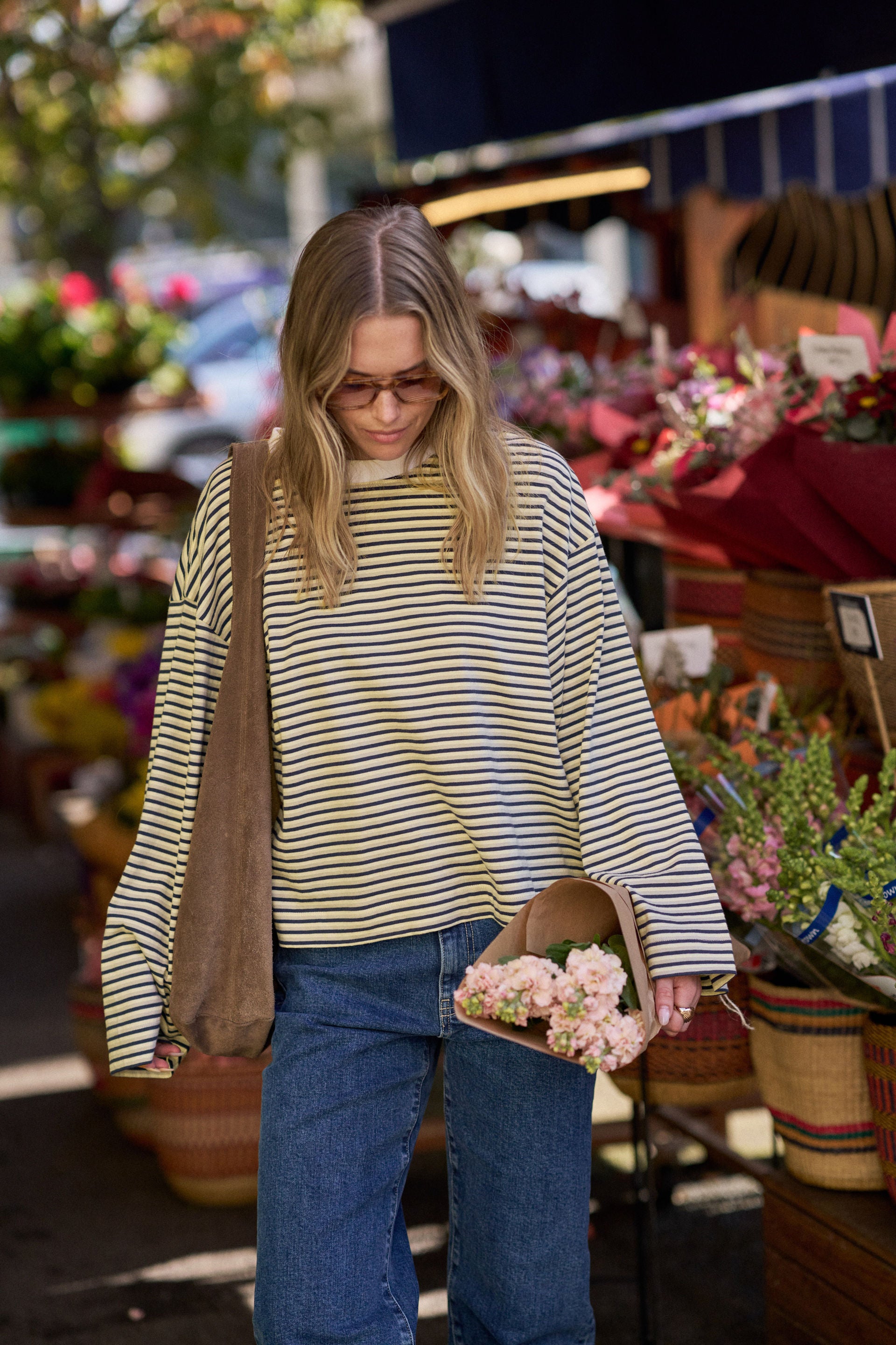 Woman shopping at an outdoor market holding flowers wearing a Ceres Life Shirt 