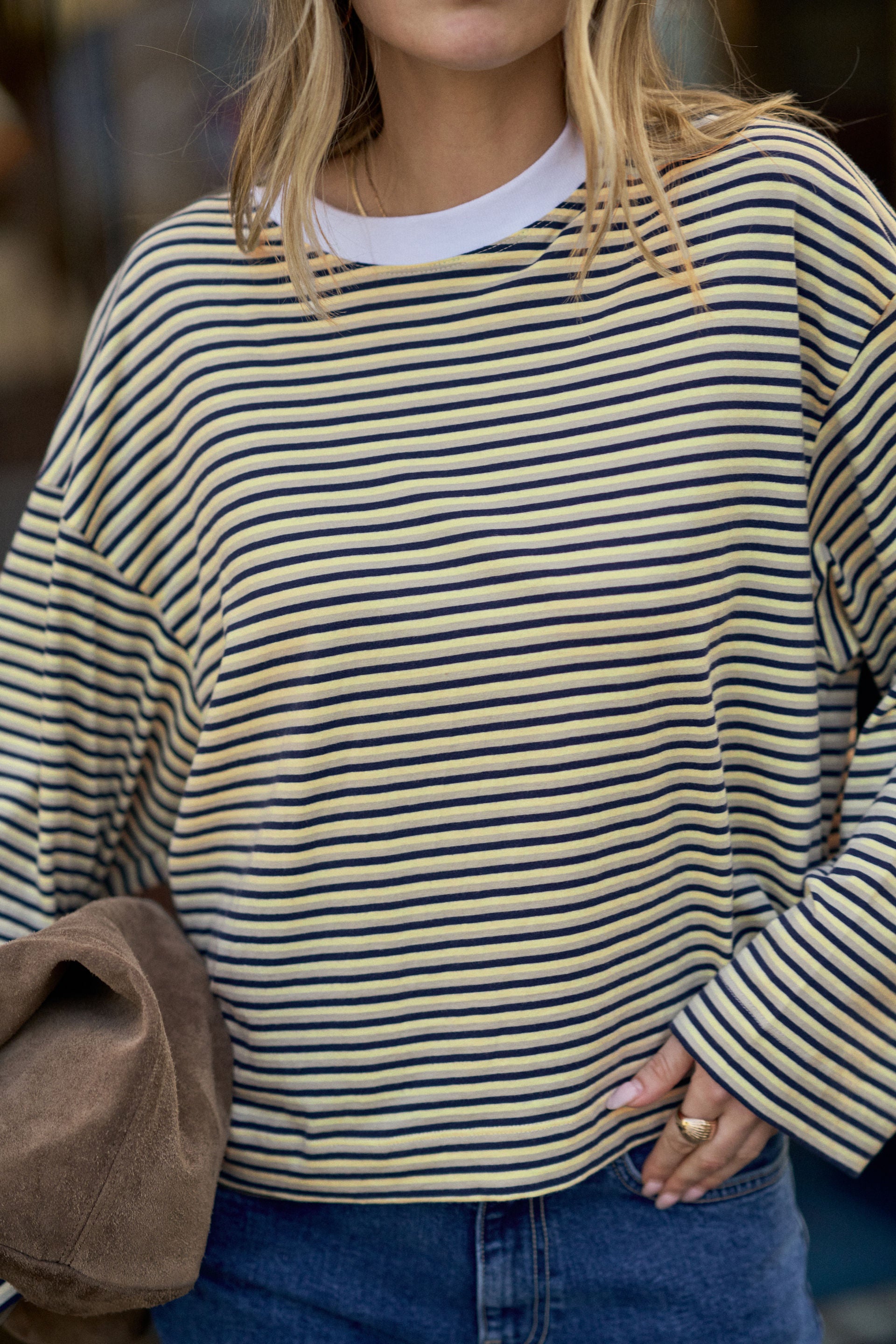 Image of Woman wearing a Ceres Life yellow and black striped sweater with a blurred background