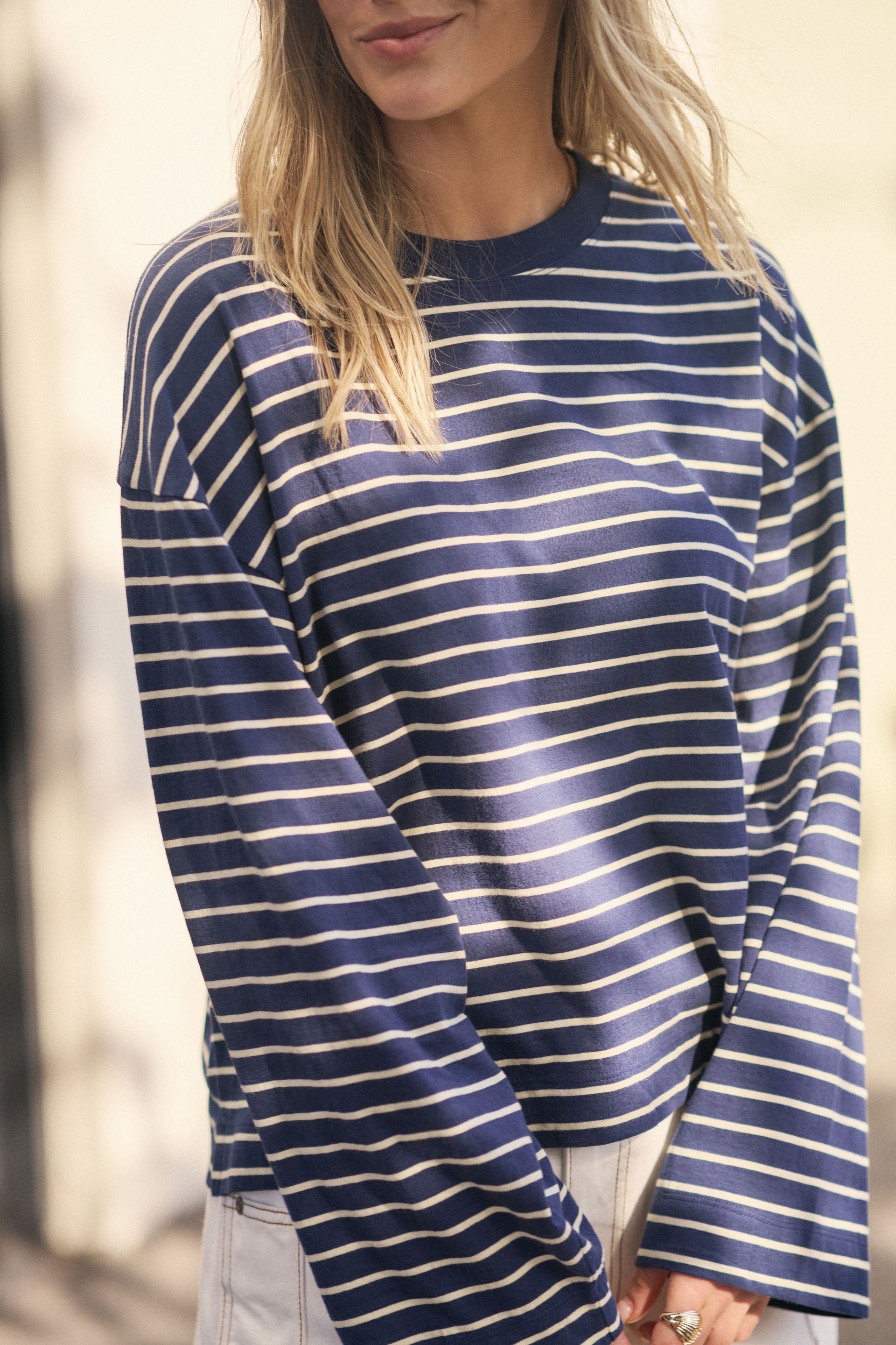 Image of Woman wearing a Ceres Life blue and white striped long-sleeve shirt with a blurred background