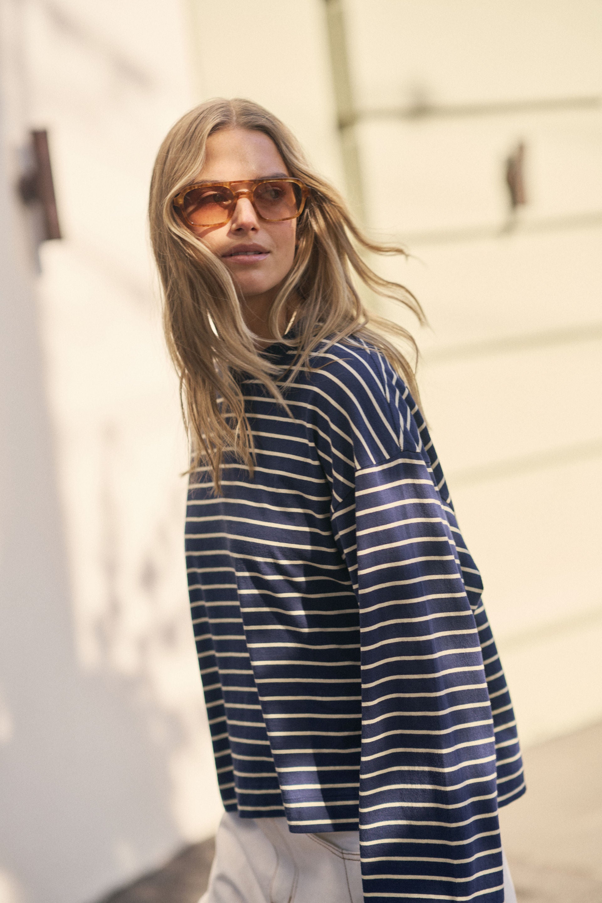 Image of Woman wearing a Ceres Life blue and white striped shirt with sunglasses against a light background