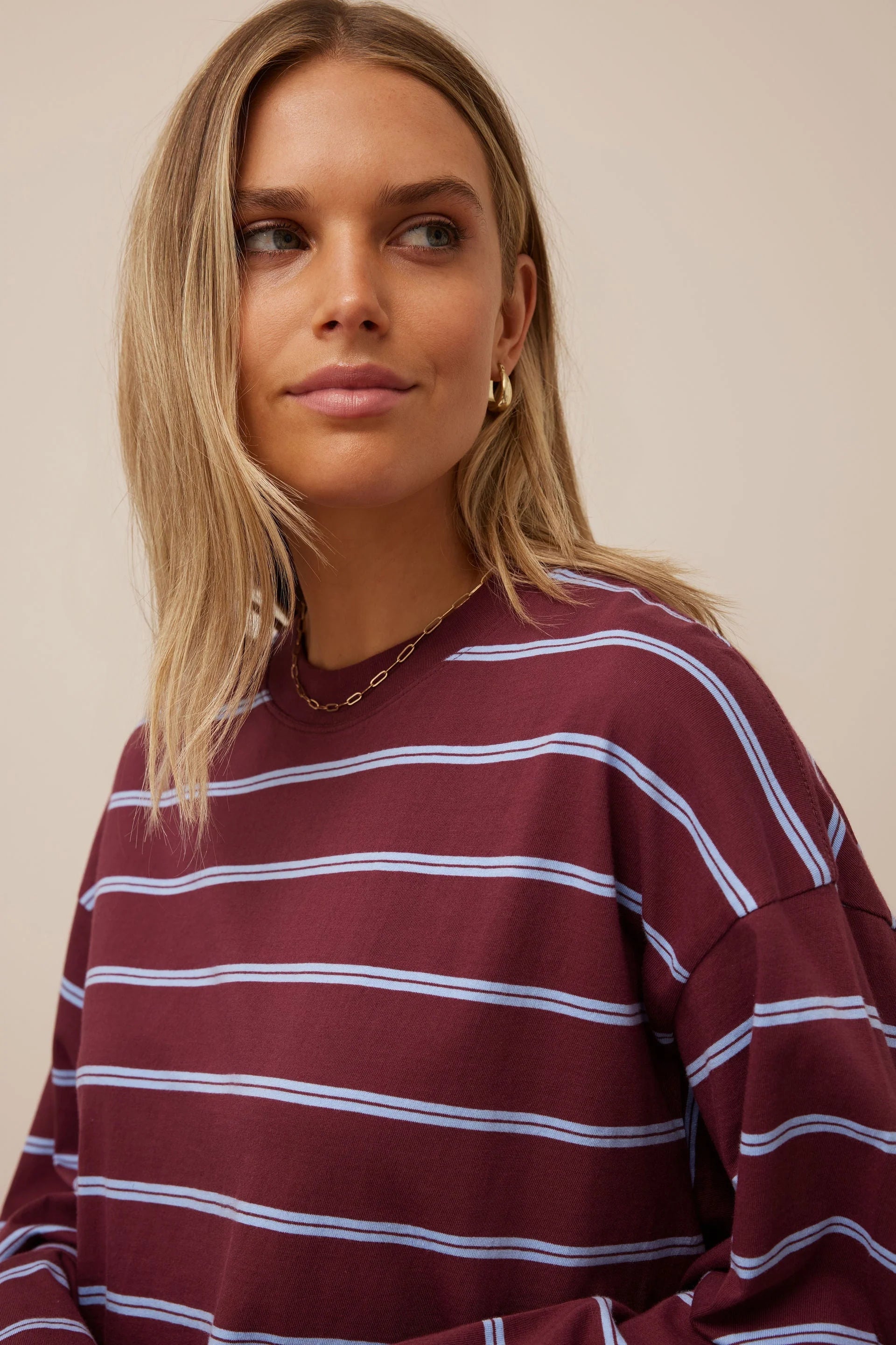 Image of Woman wearing Ceres Life long sleeve burgundy and navy stripe paired with denim jeans and sneakers 