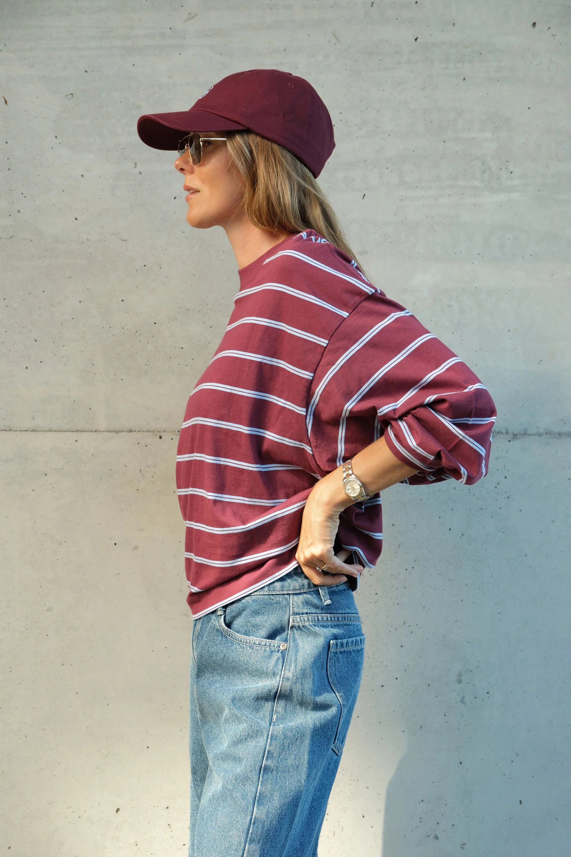 Image of Woman wearing Ceres Life long sleeve burgundy and navy stripe paired with denim jeans and sneakers 