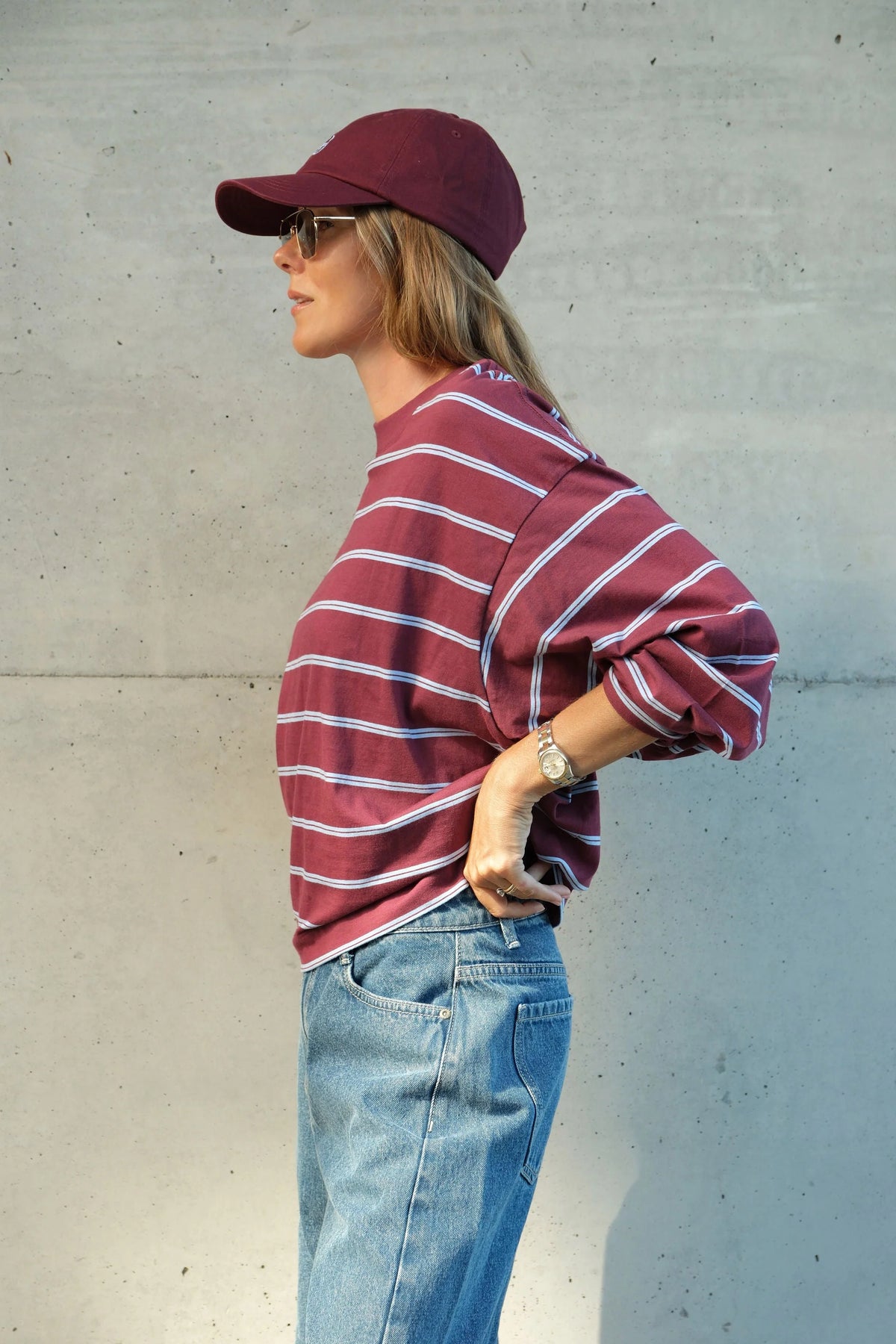 Woman wearing Ceres Life long sleeve burgundy and navy stripe paired with denim jeans and sneakers 