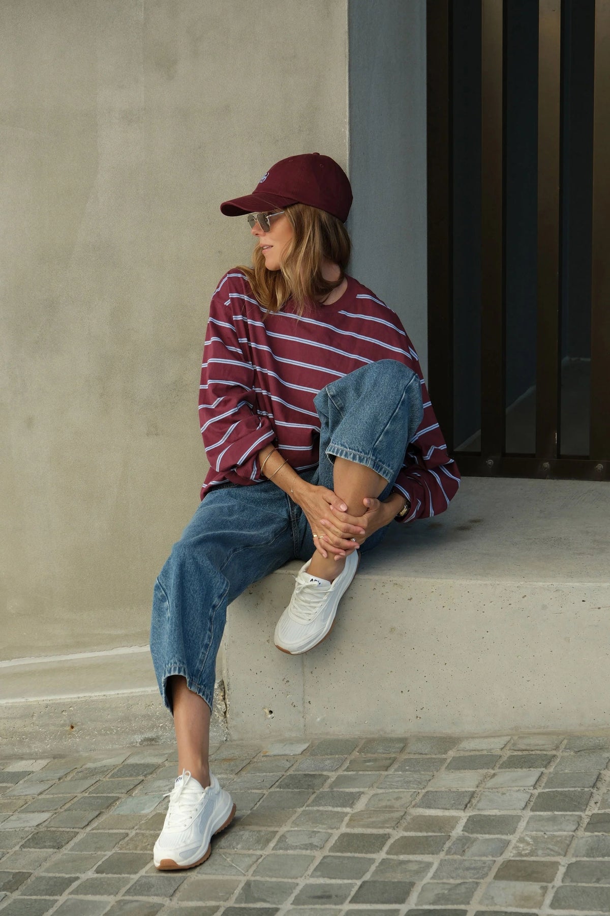 Woman wearing Ceres Life long sleeve burgundy and navy stripe paired with denim jeans and sneakers 