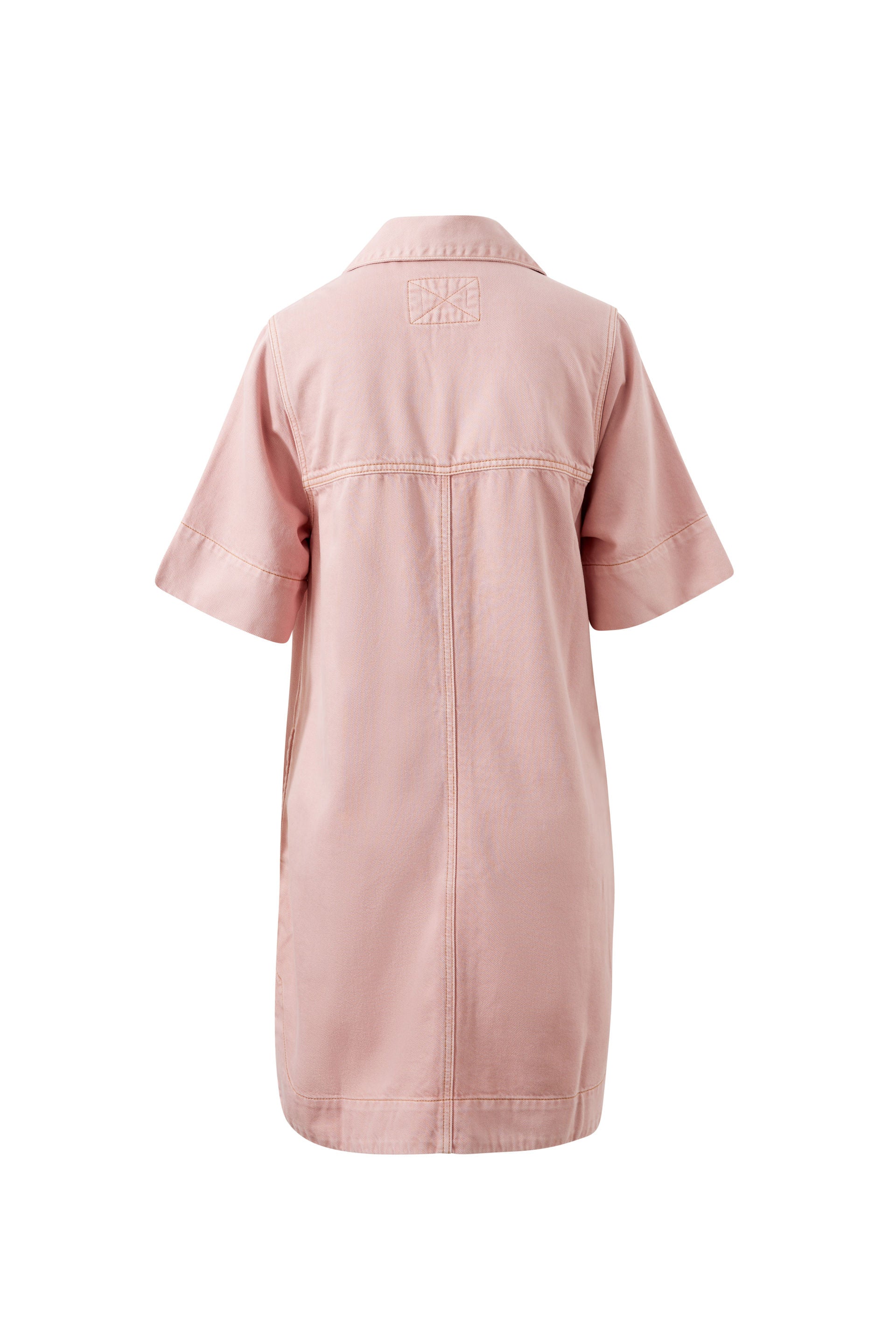 Image of Model wears a relaxed pink denim shirt dress featuring a button-through front, short sleeves, chest pockets and a collared neckline, styled with black sandals.
