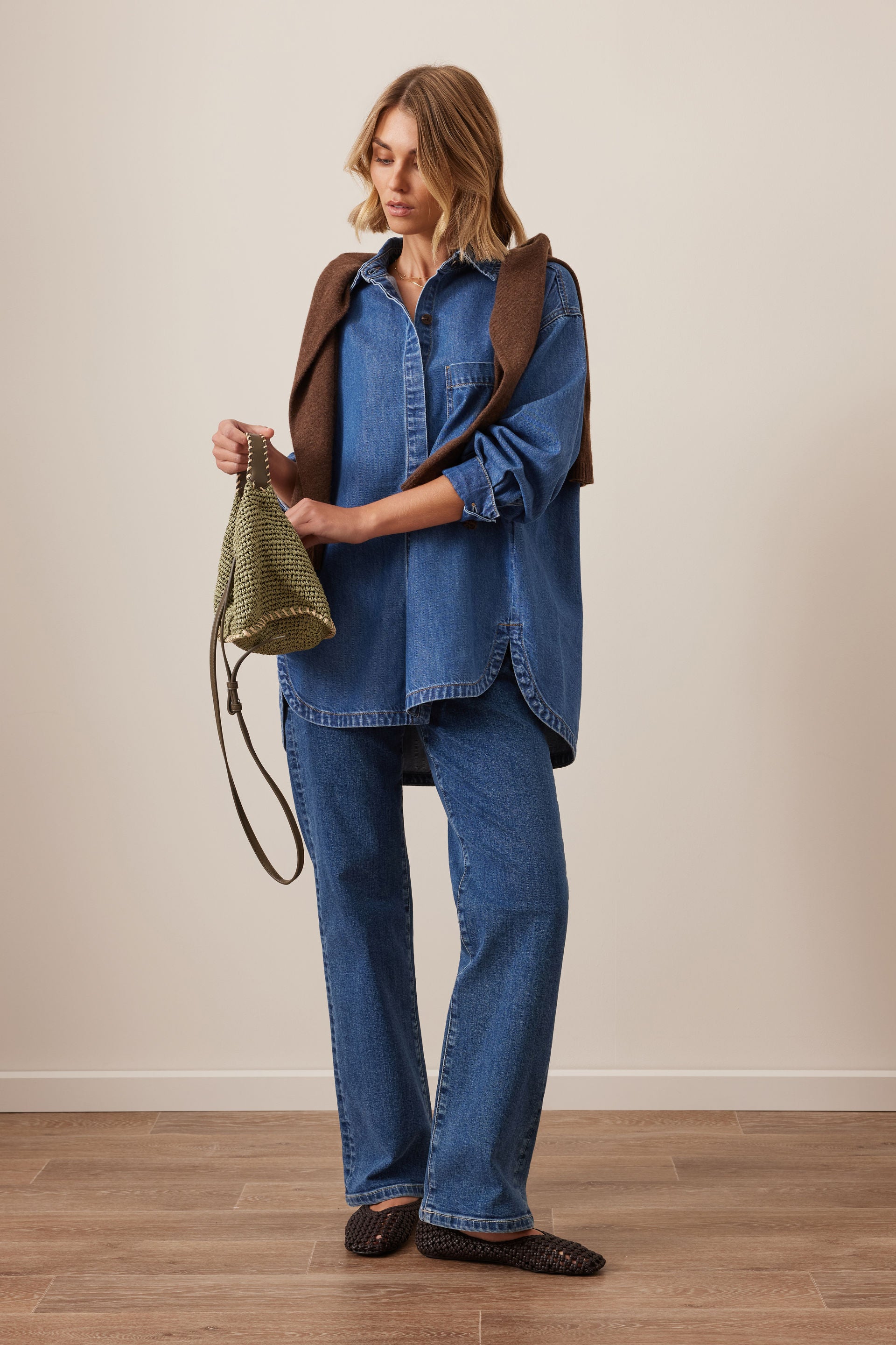 Image of Woman wearing a Ceres Life blue denim outfit with a brown leather bag against a plain background