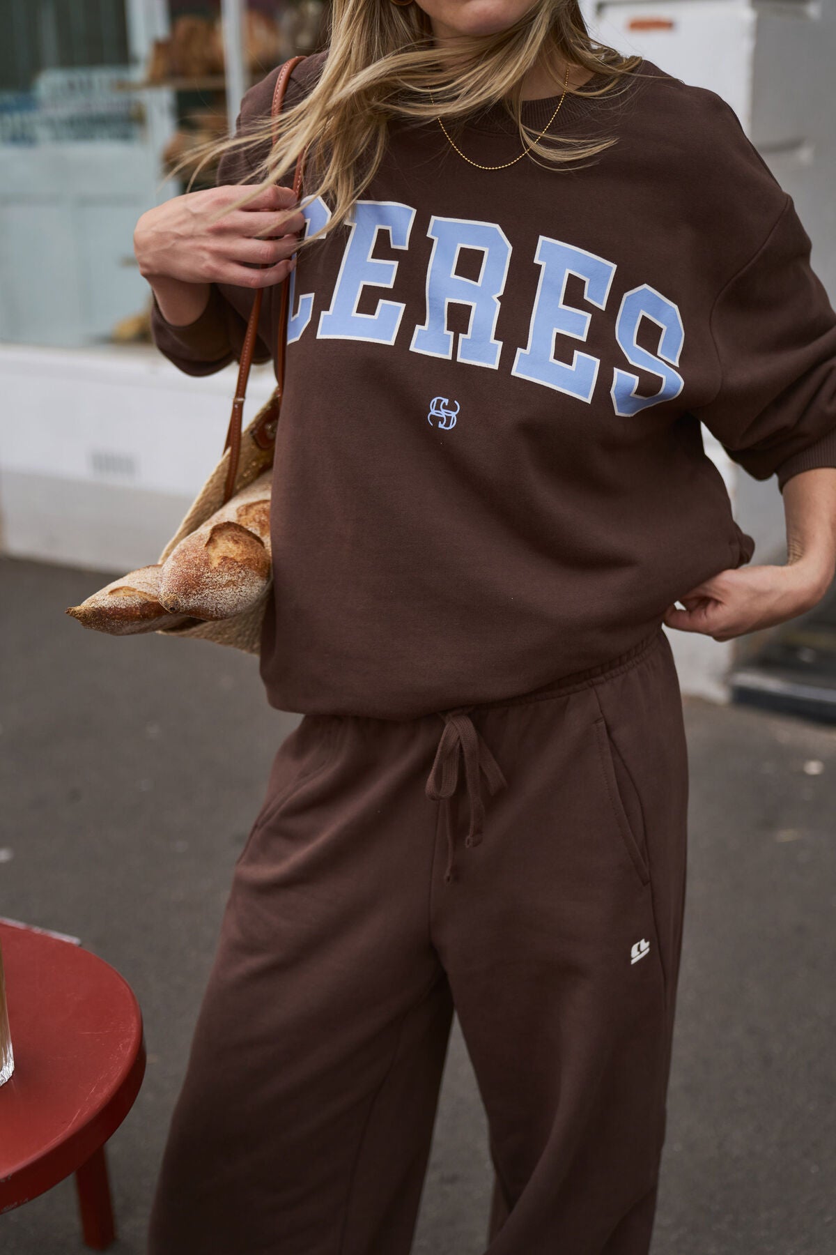 Image of Person wearing a brown 'CERES' sweatshirt and pants outdoors.