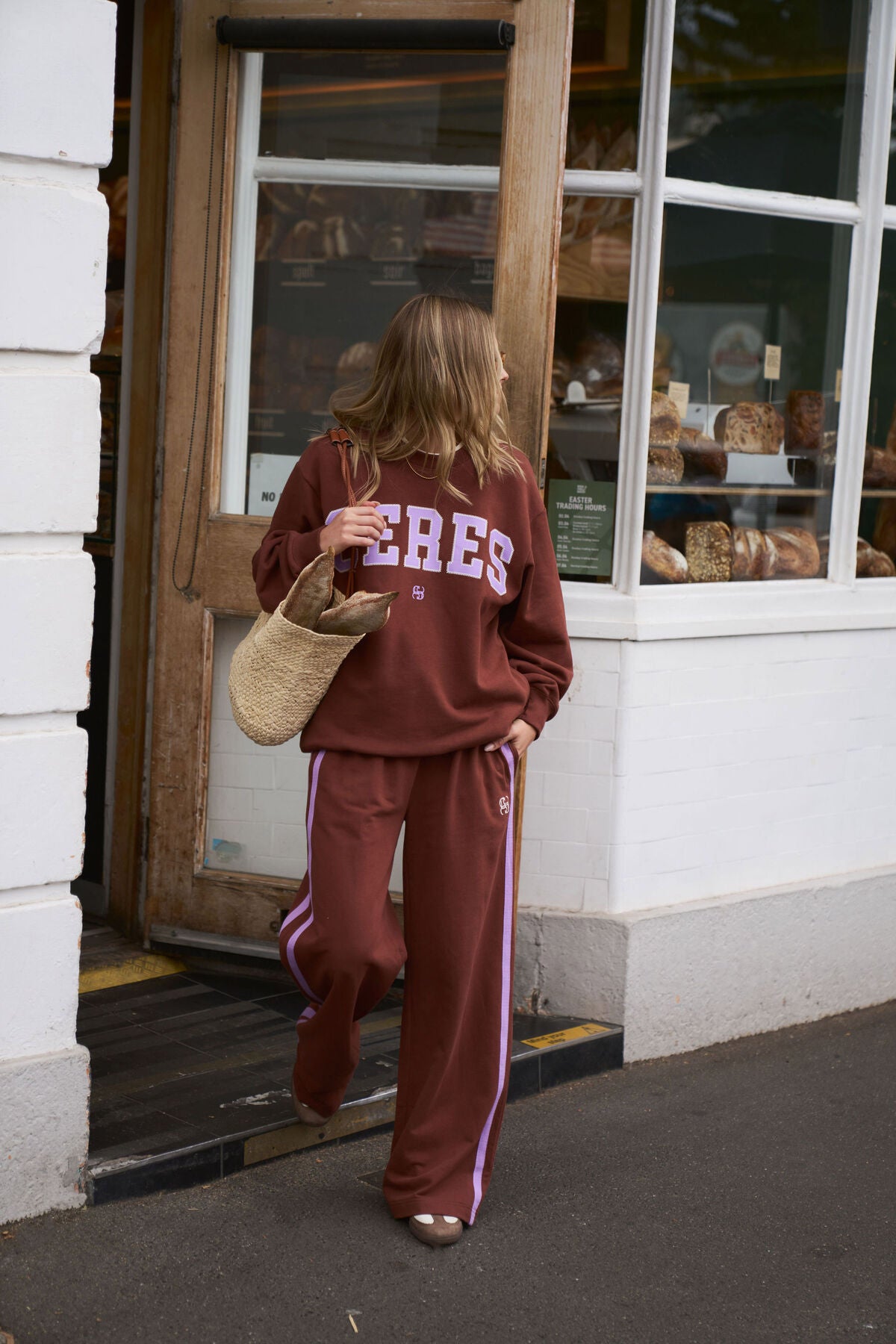 Woman wearing a brown tracksuit with 'Céres' text, standing outside a building.