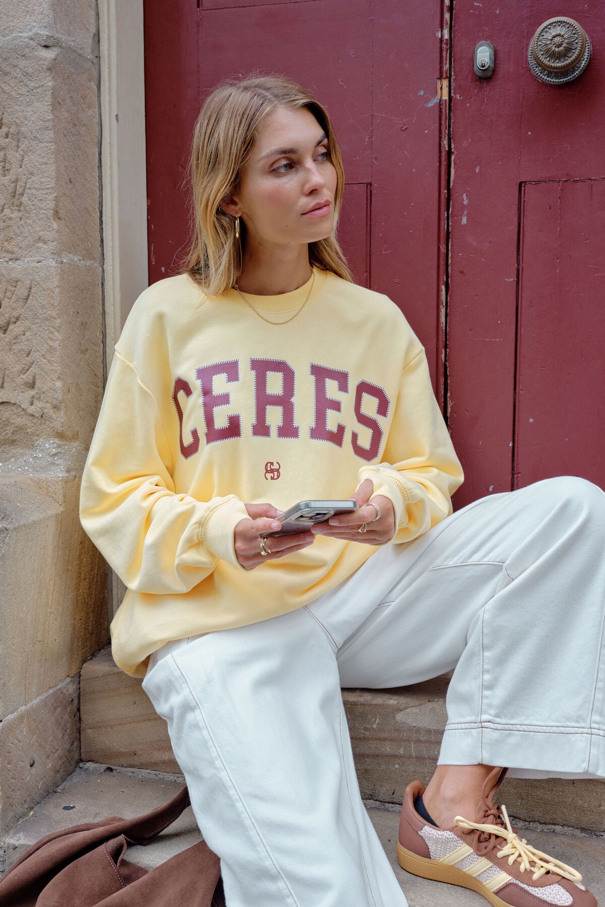 Image of Woman wearing a yellow 'CERES' sweatshirt sitting on steps.