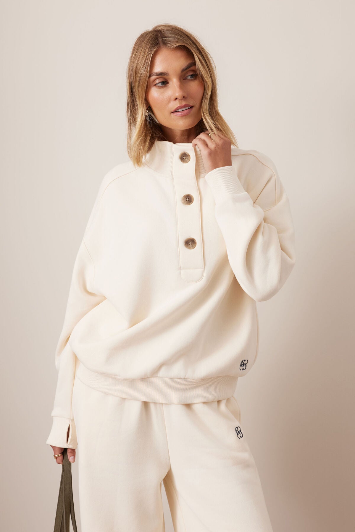 Woman wearing a Ceres Life cream-colored outfit with a plain background