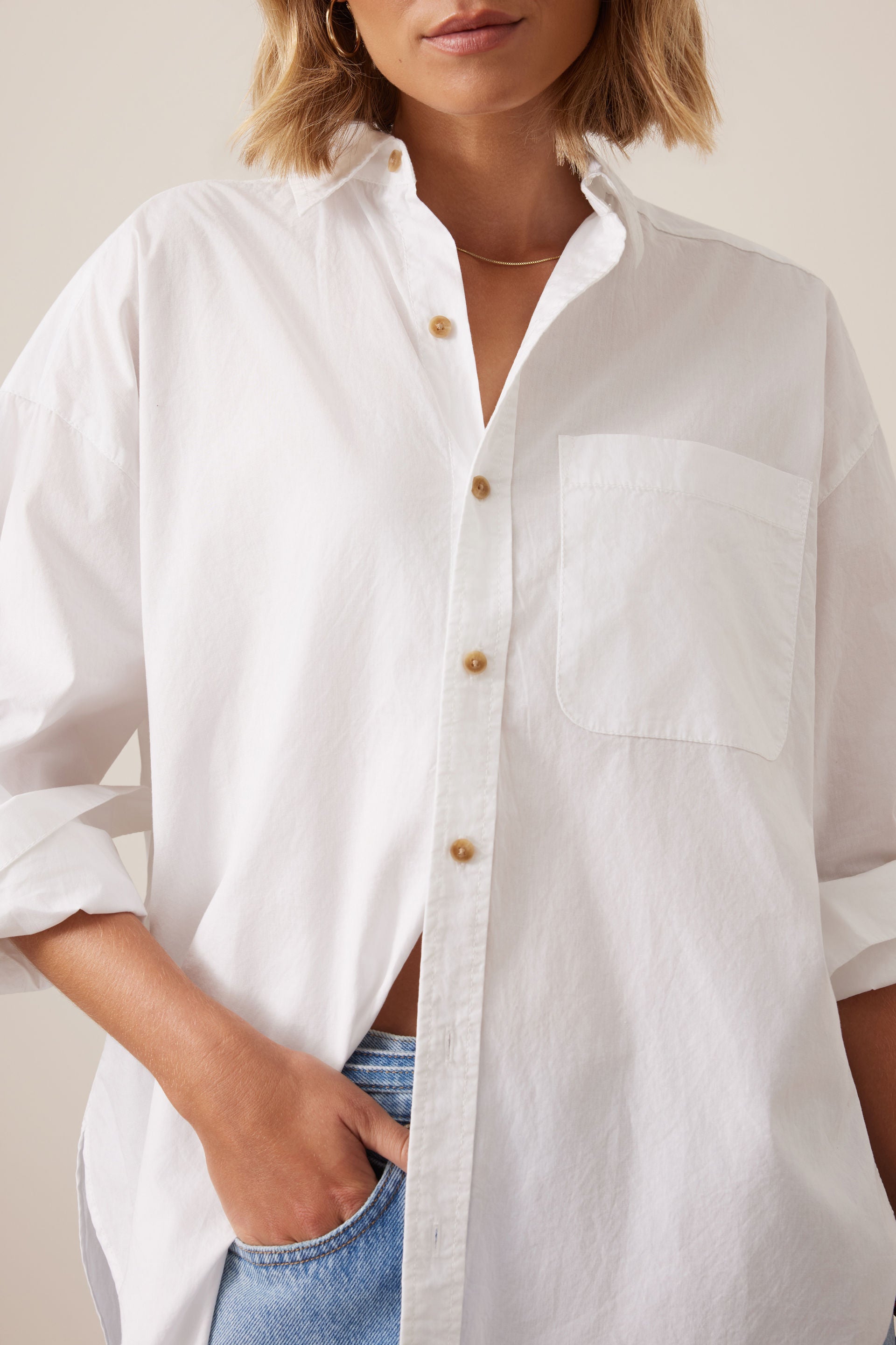 Image of Woman wearing a Ceres Life white button-up shirt with a neutral background