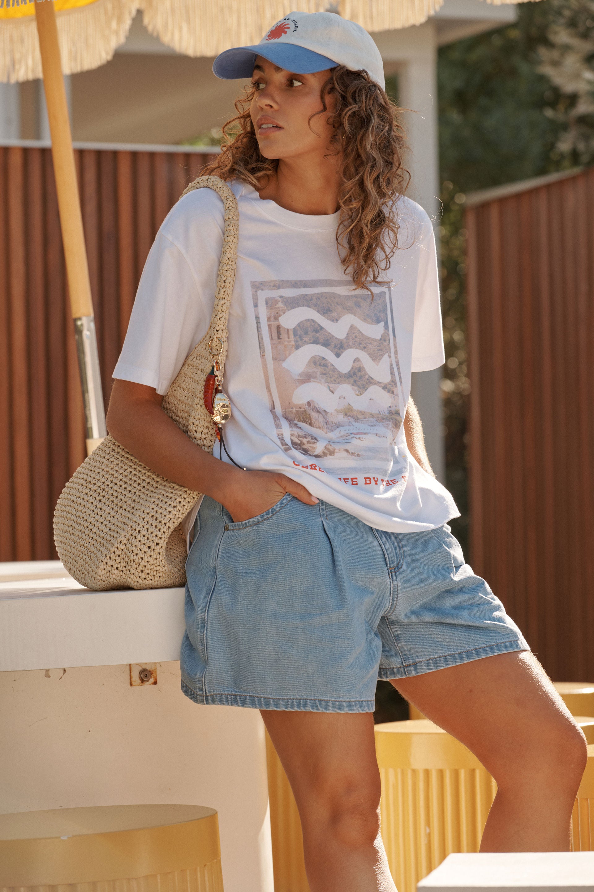 Woman wearing a Ceres Life graphic t-shirt and denim shorts, standing outdoors.