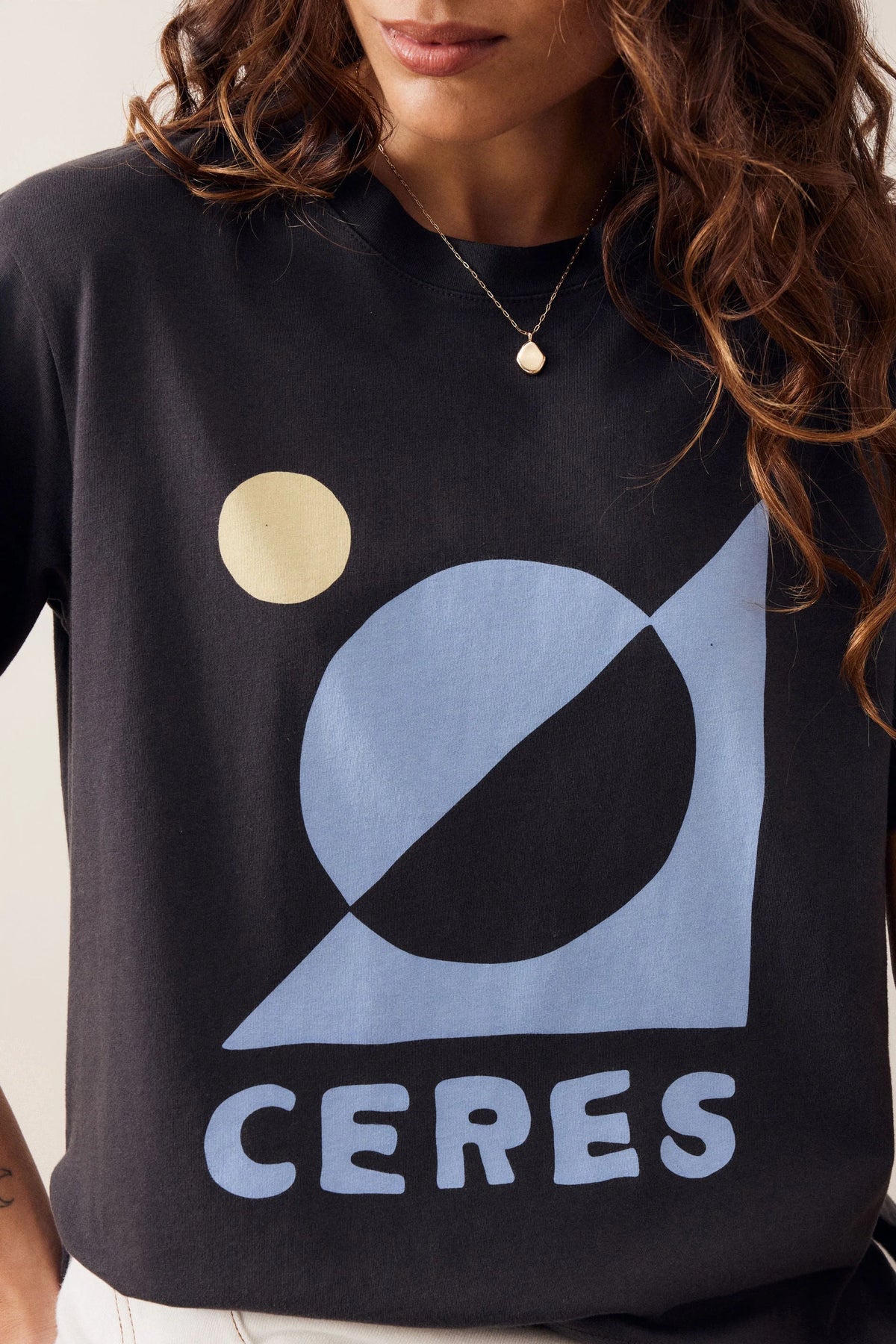 Woman wearing a Ceres graphic tshirt paired with a plain pair of white jeans on a plain background