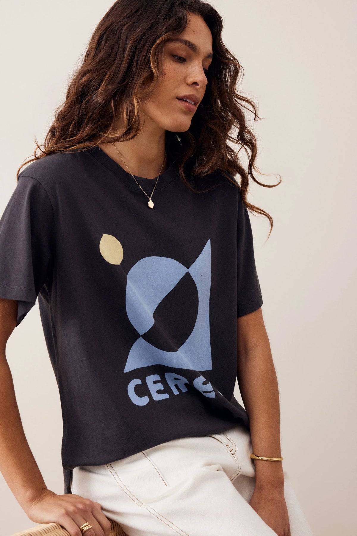 Woman wearing a Ceres graphic tshirt paired with a plain pair of white jeans on a plain background