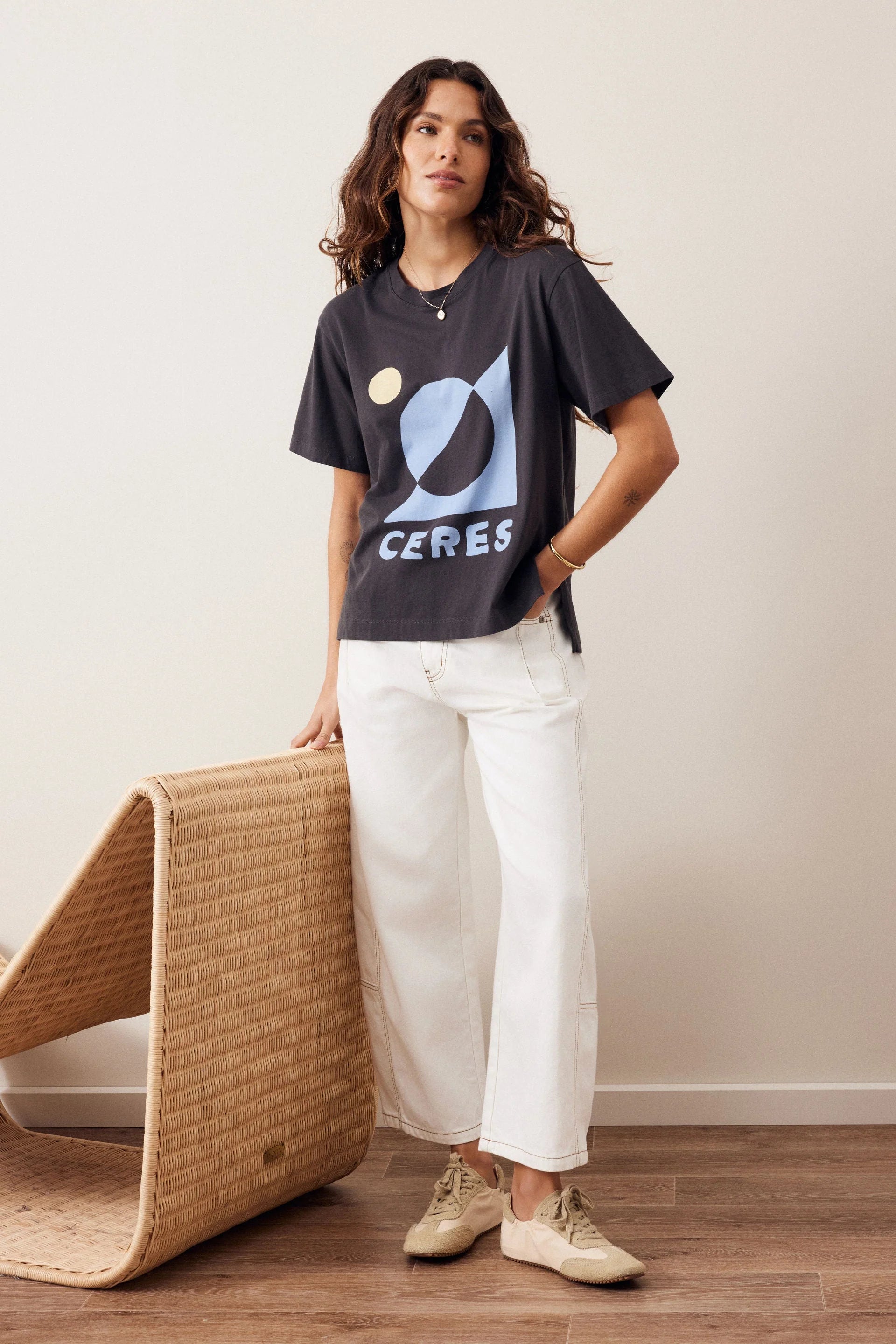 Image of Woman wearing a Ceres graphic tshirt paired with a plain pair of white jeans on a plain background