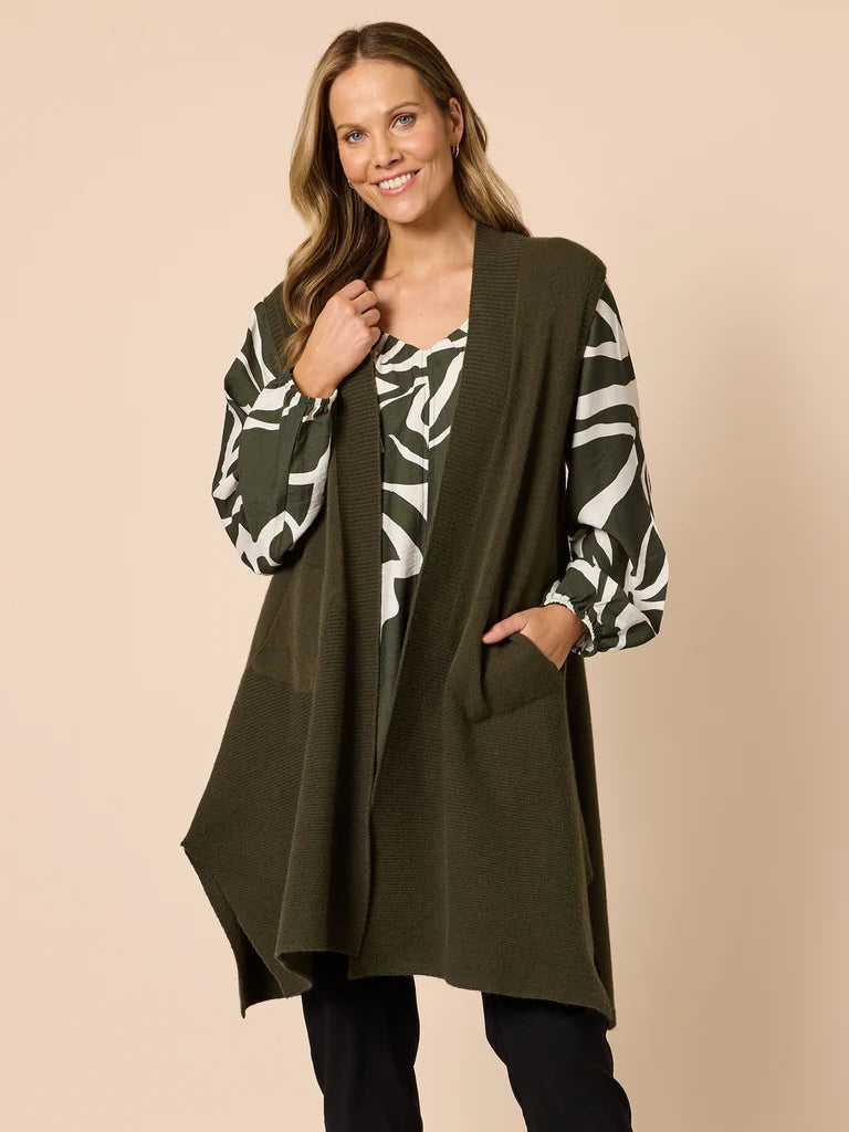 Woman wearing a Clarity green cardigan over a patterned top on a beige background