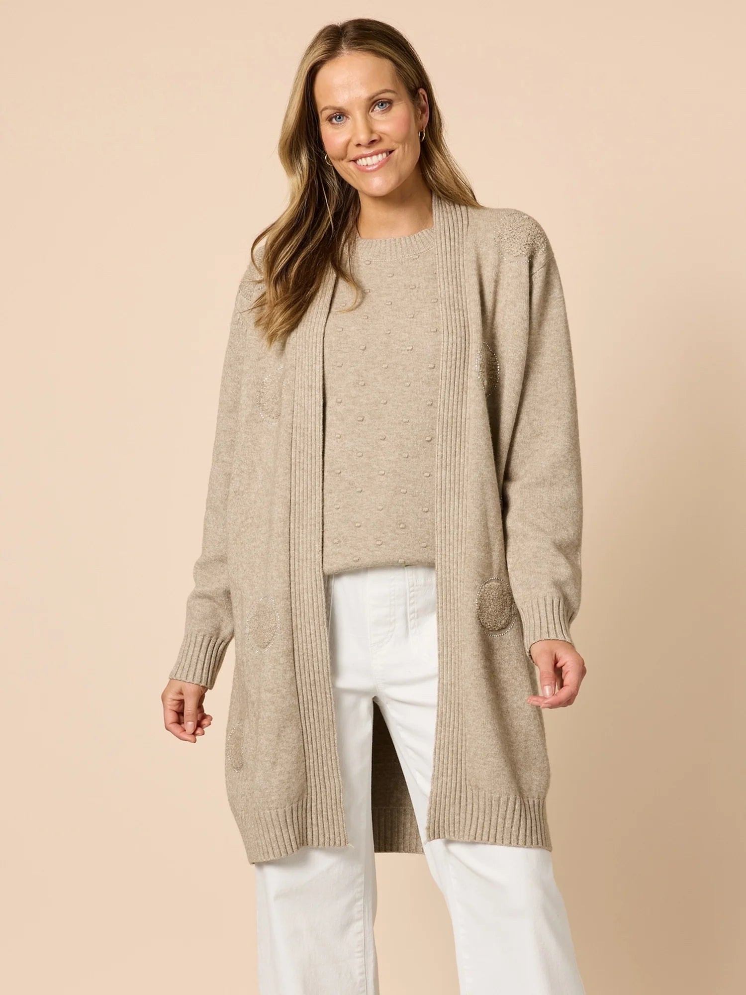 Image of Woman wearing a Clarity beige long cardigan over a white top on a beige background