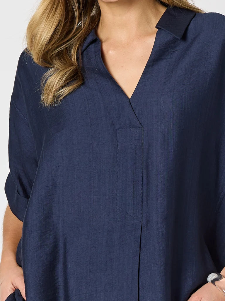 A close-up of a woman wearing a Clarity dark navy blue linen shirt with a V-neck and collar.