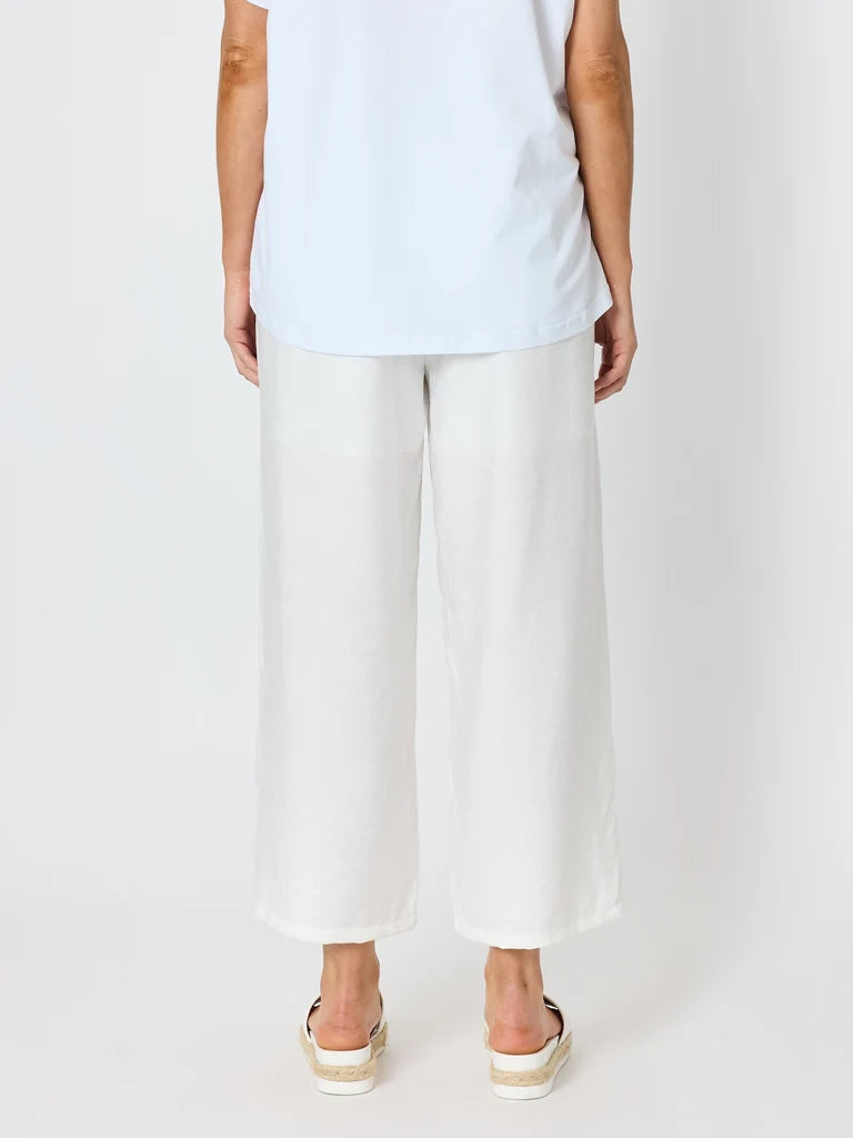 Image of A model shown from the back wearing Clarity white wide-leg cropped pants, a light blue t-shirt, and white espadrille sandals against a plain white studio background.