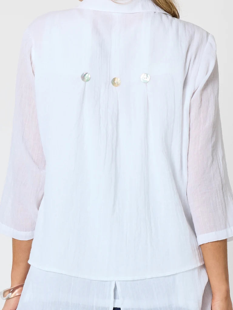A close-up of a Clarity white linen blouse with three iridescent shell buttons on the back, worn by a woman