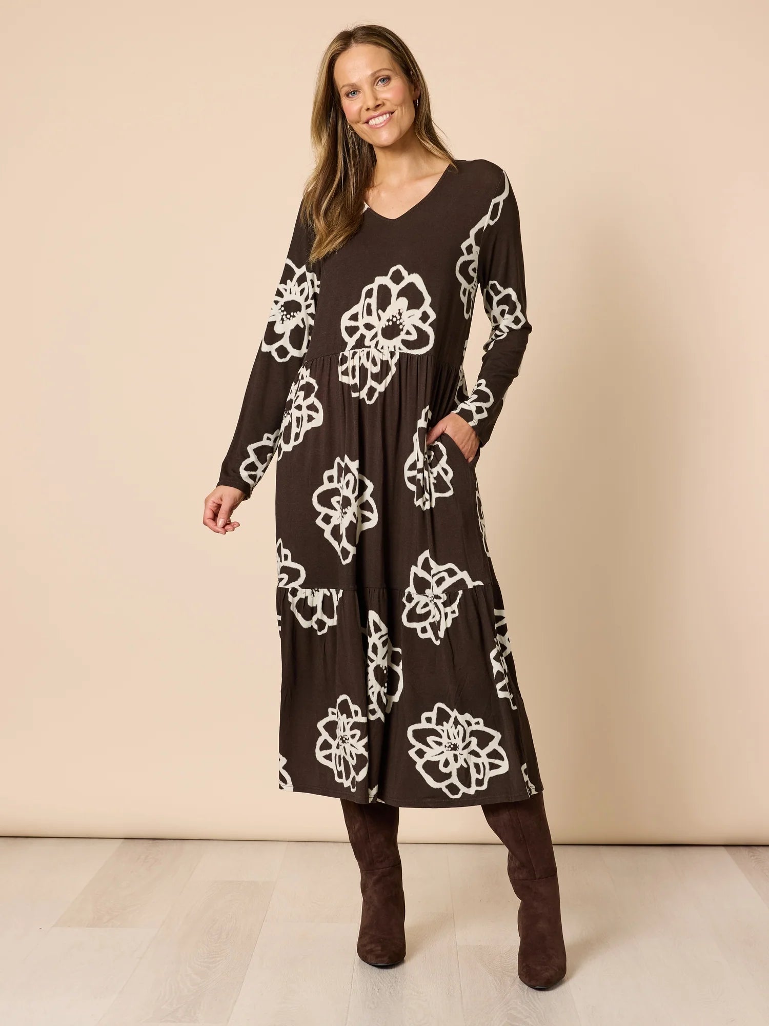 Image of Woman wearing a Clarity long black dress with white floral patterns on a beige background