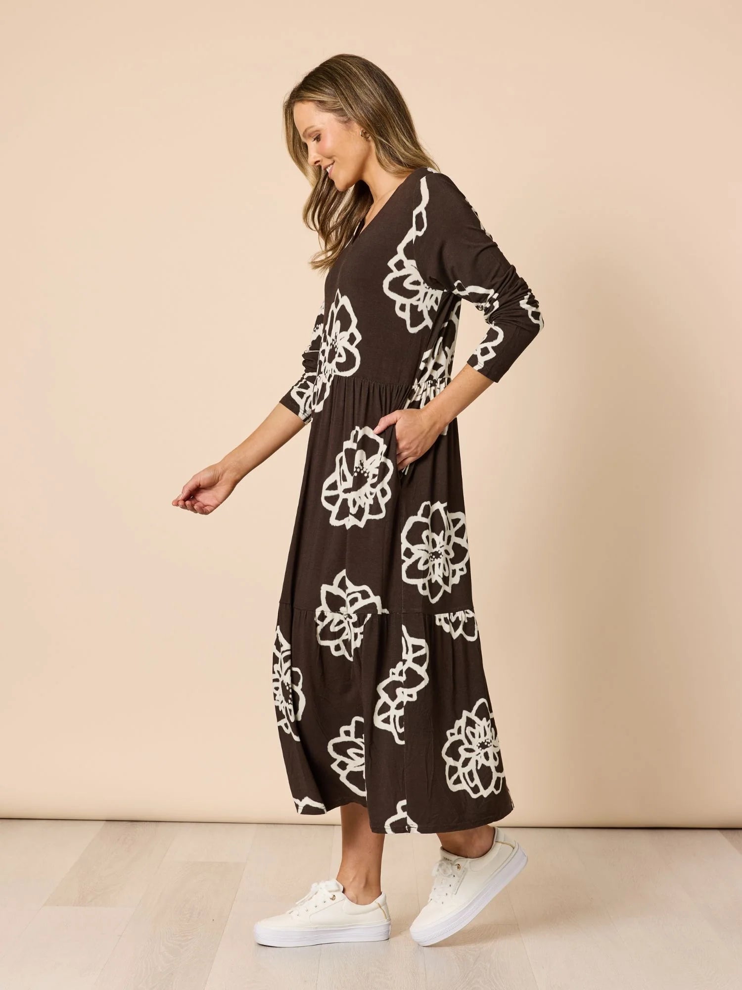 Image of Woman wearing a Clarity brown dress with white floral patterns against a beige background