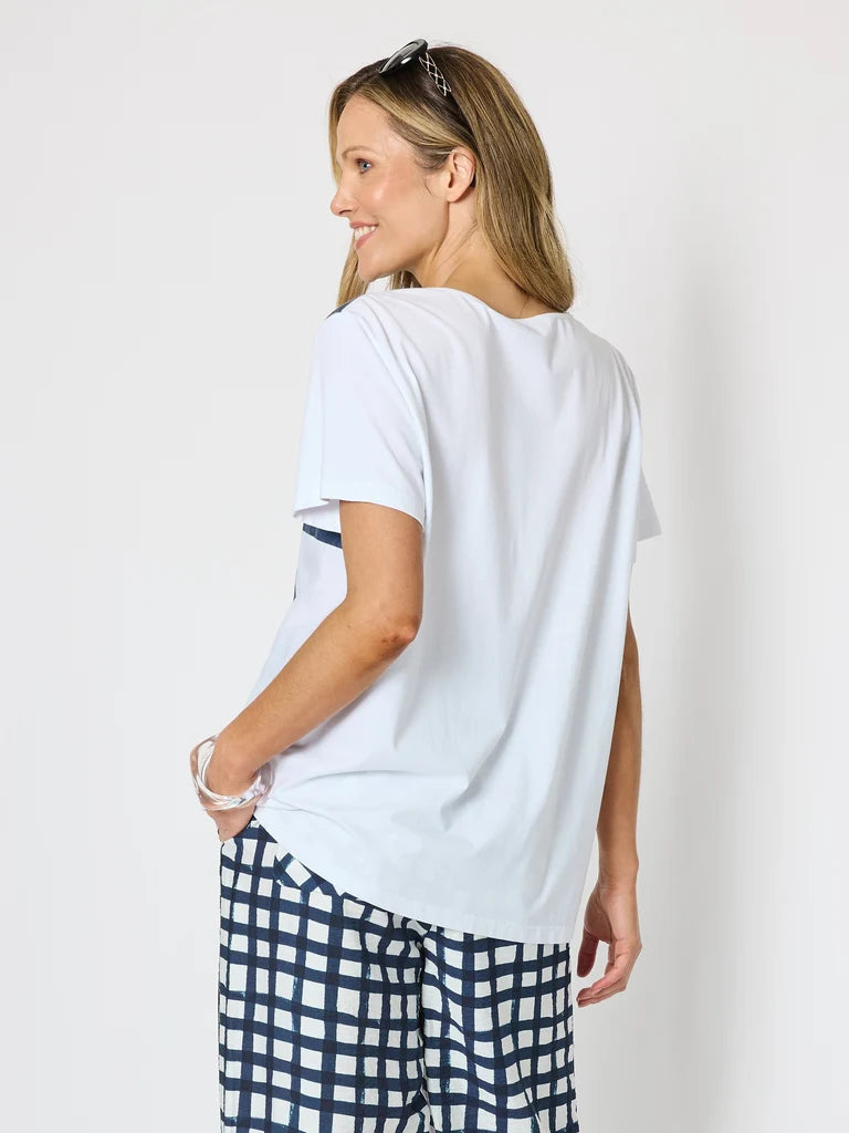 Image of A woman shown from the back wearing a Clarity white short-sleeve t-shirt and navy and white checkered pants, standing against a plain white background.