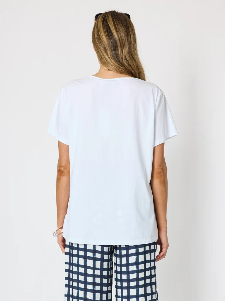 Image of A woman viewed from the back wearing a Clarity plain white short-sleeve t-shirt and navy-and-white checkered pants, standing against a light gray studio background.
