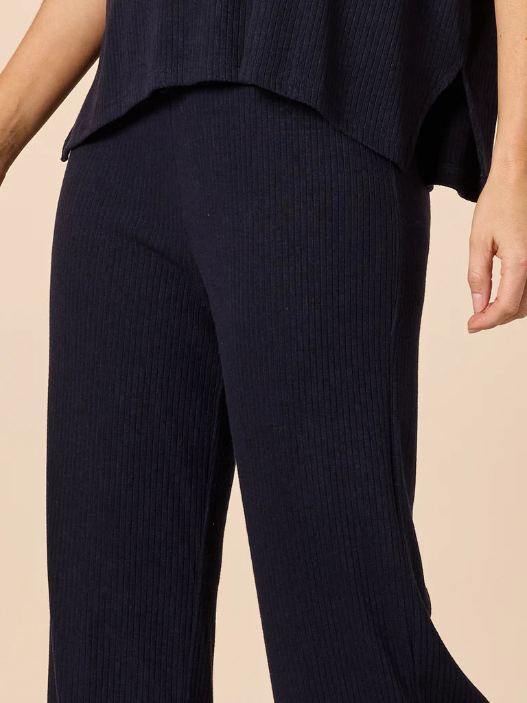 Image of Woman wearing Clarity Navy blue ribbed pants worn by a person on a beige background