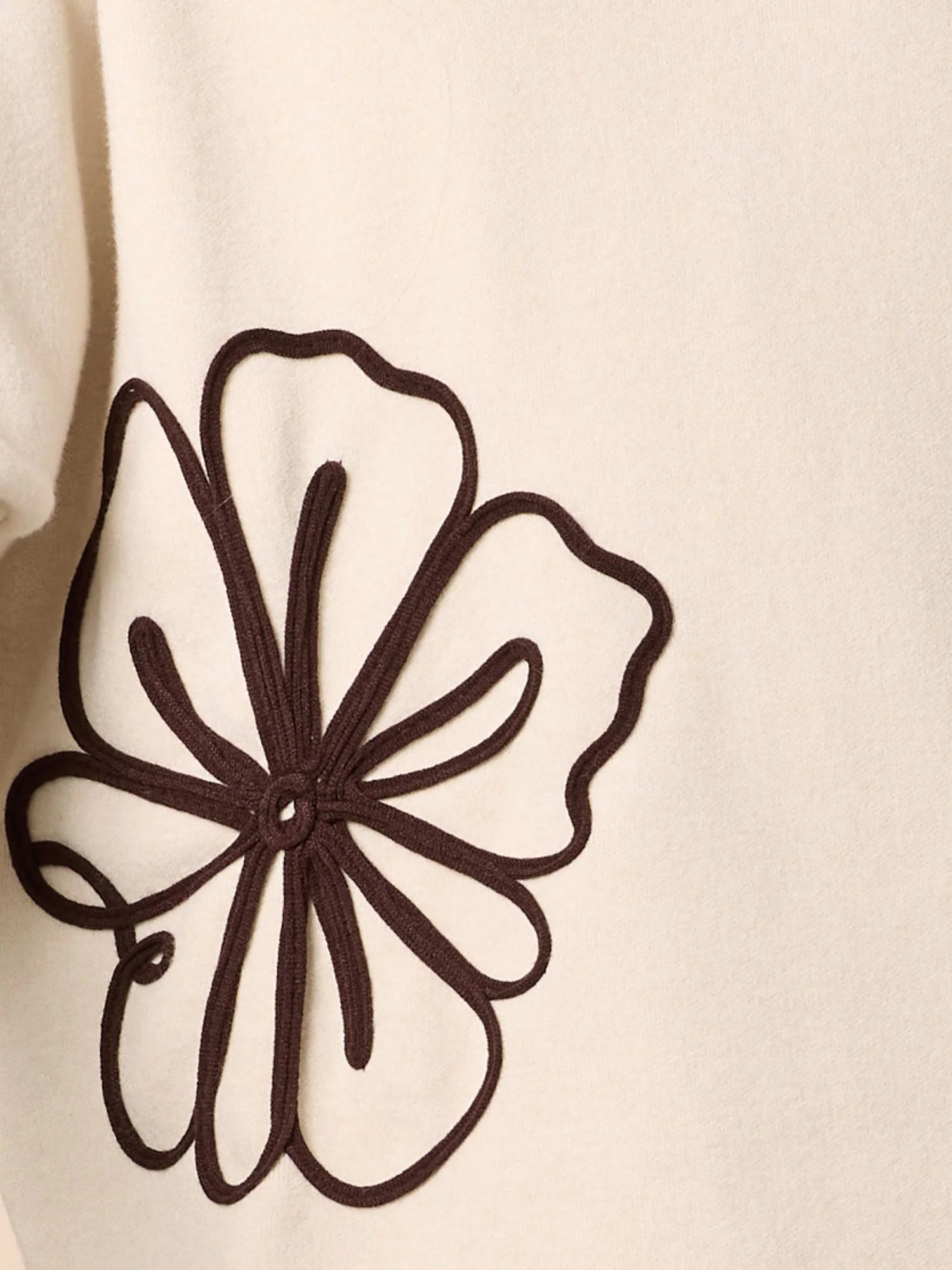 Black floral embroidery on a beige fabric background