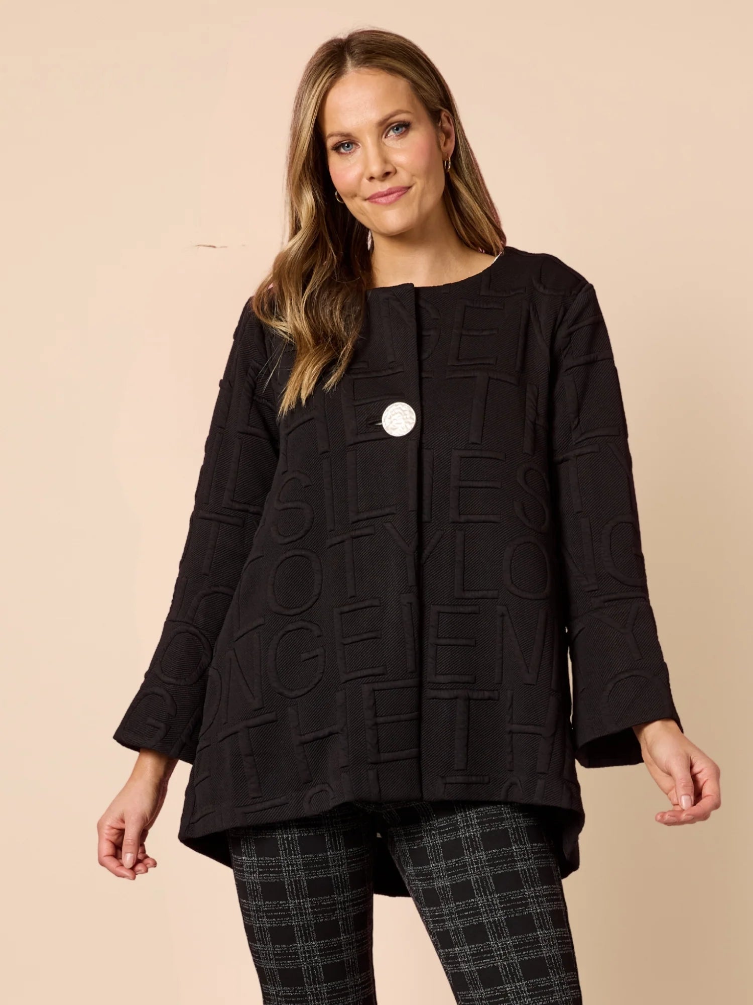 Image of Woman wearing a Clarity black textured jacket with a beige background