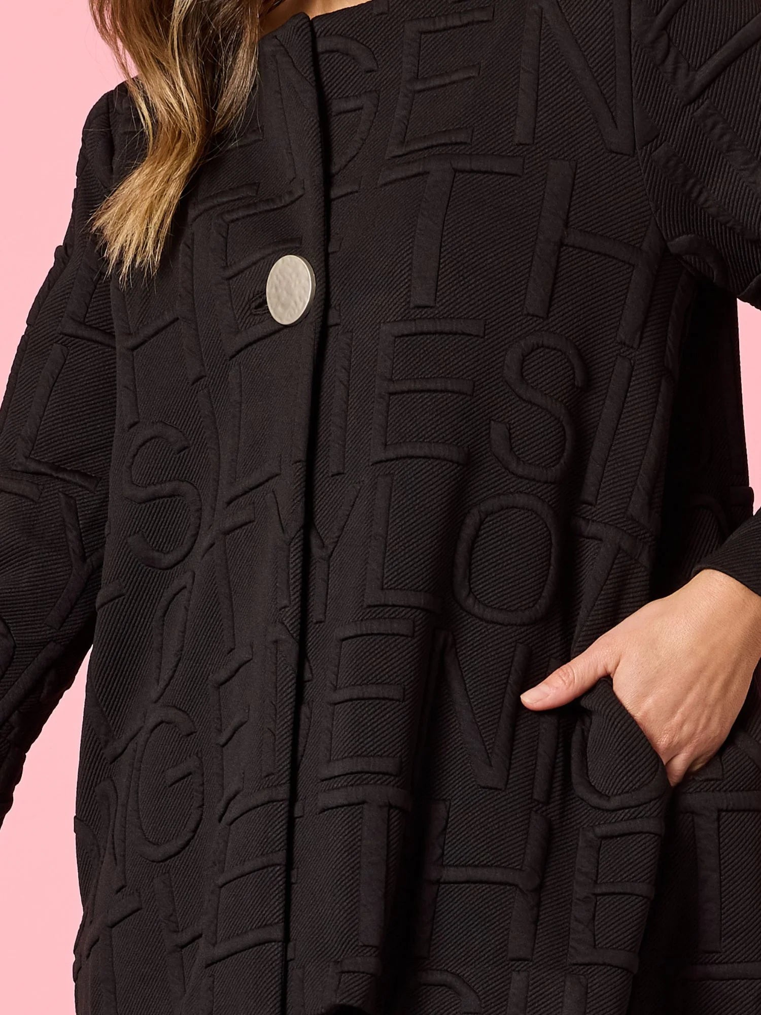 Image of Clarity Black textured coat with brand logo on a pink background