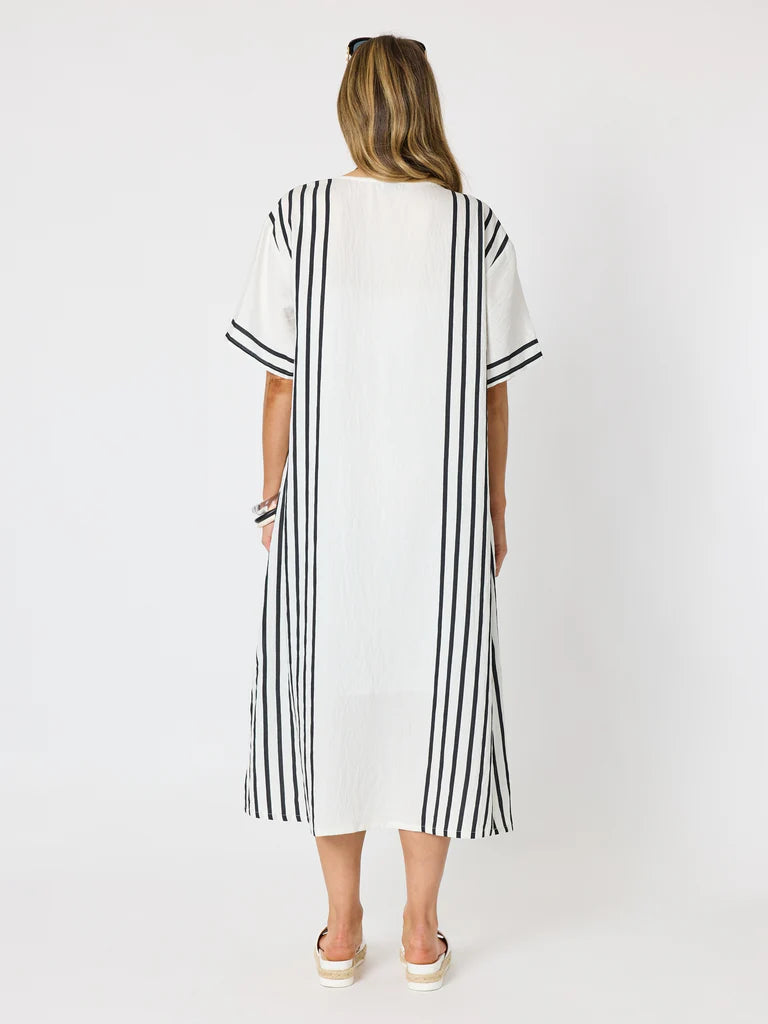 A woman viewed from the back wearing a Clarity white midi dress with vertical black stripes on the sleeves, sides, and hem, paired with white platform sandals against a plain white studio background.