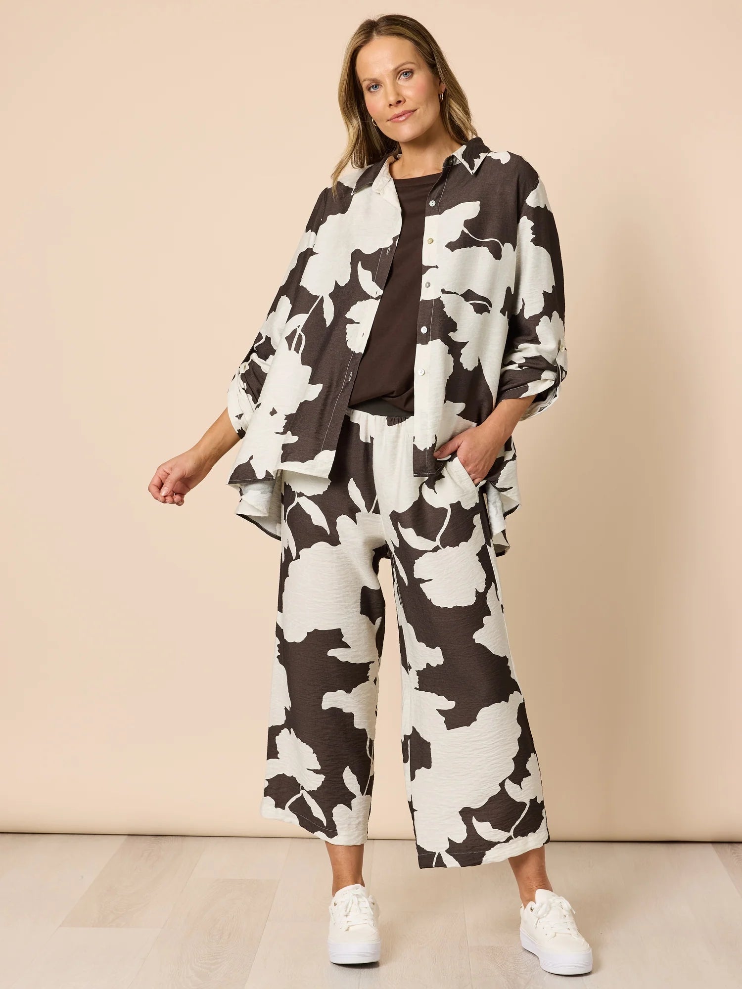 Woman wearing a Clarity black and white floral outfit on a beige background