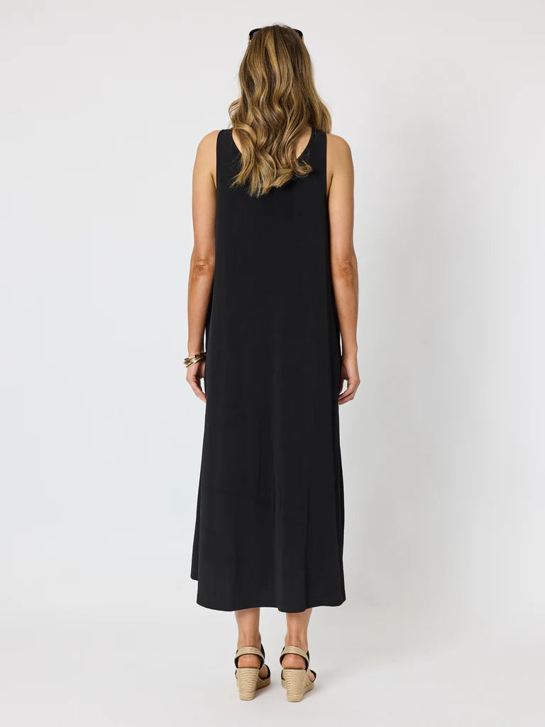 Image of A woman viewed from the back wearing a Clarity sleeveless black midi dress and beige platform sandals against a plain light gray studio background.