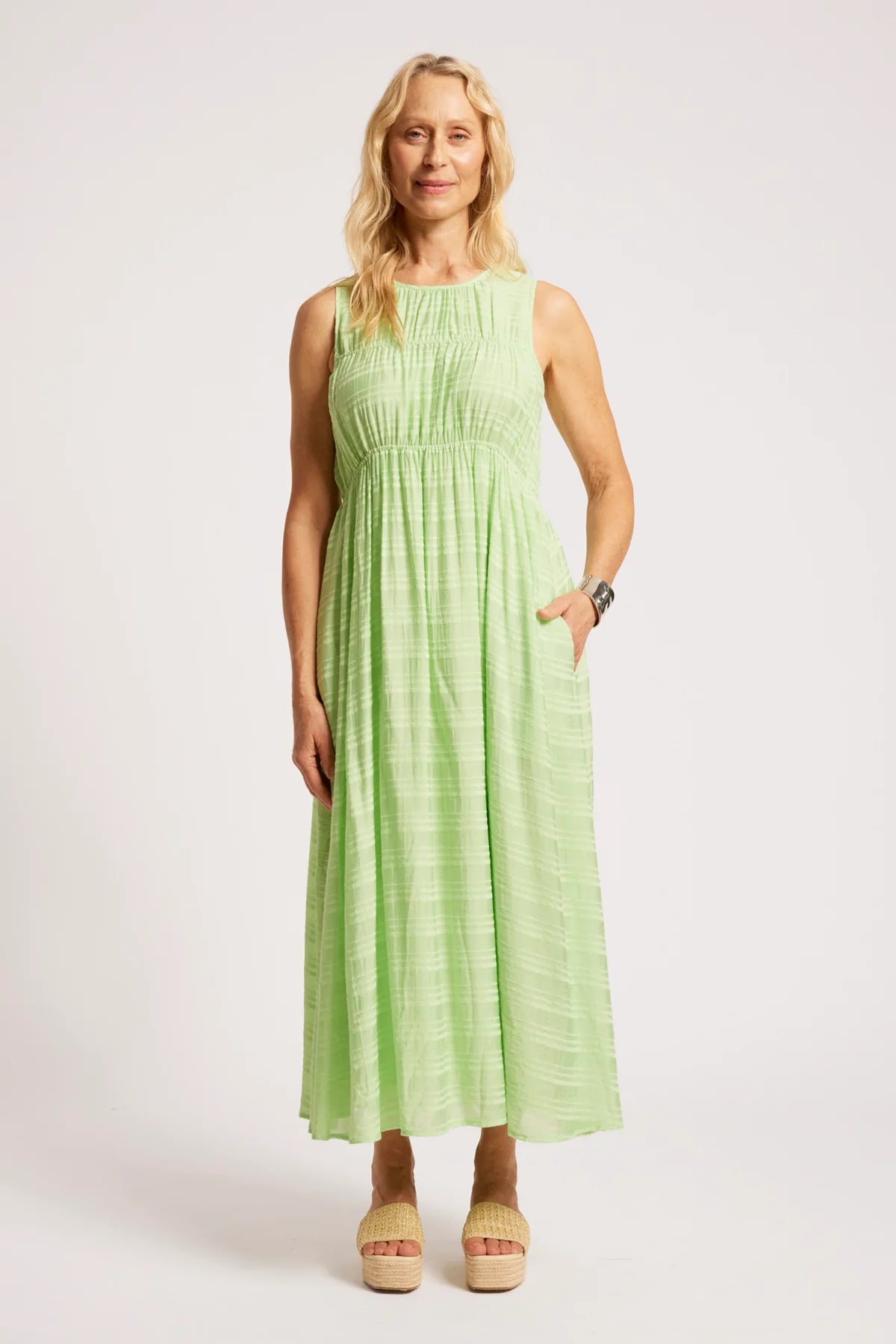 A woman modeling a Eb & Ive sleeveless light green maxi dress with a textured crinkle pattern, standing against a plain light gray studio background.