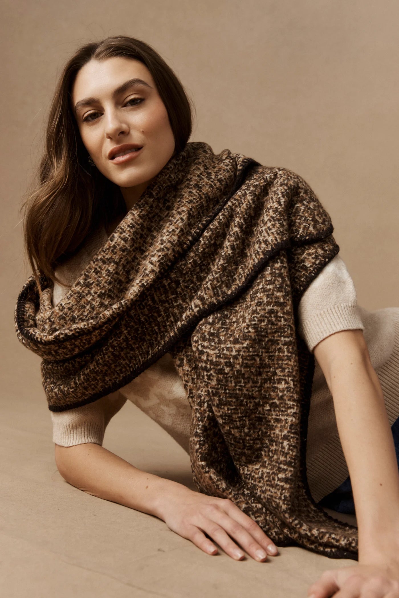 Woman wearing a Eb & Ive brown patterned shawl on a beige background