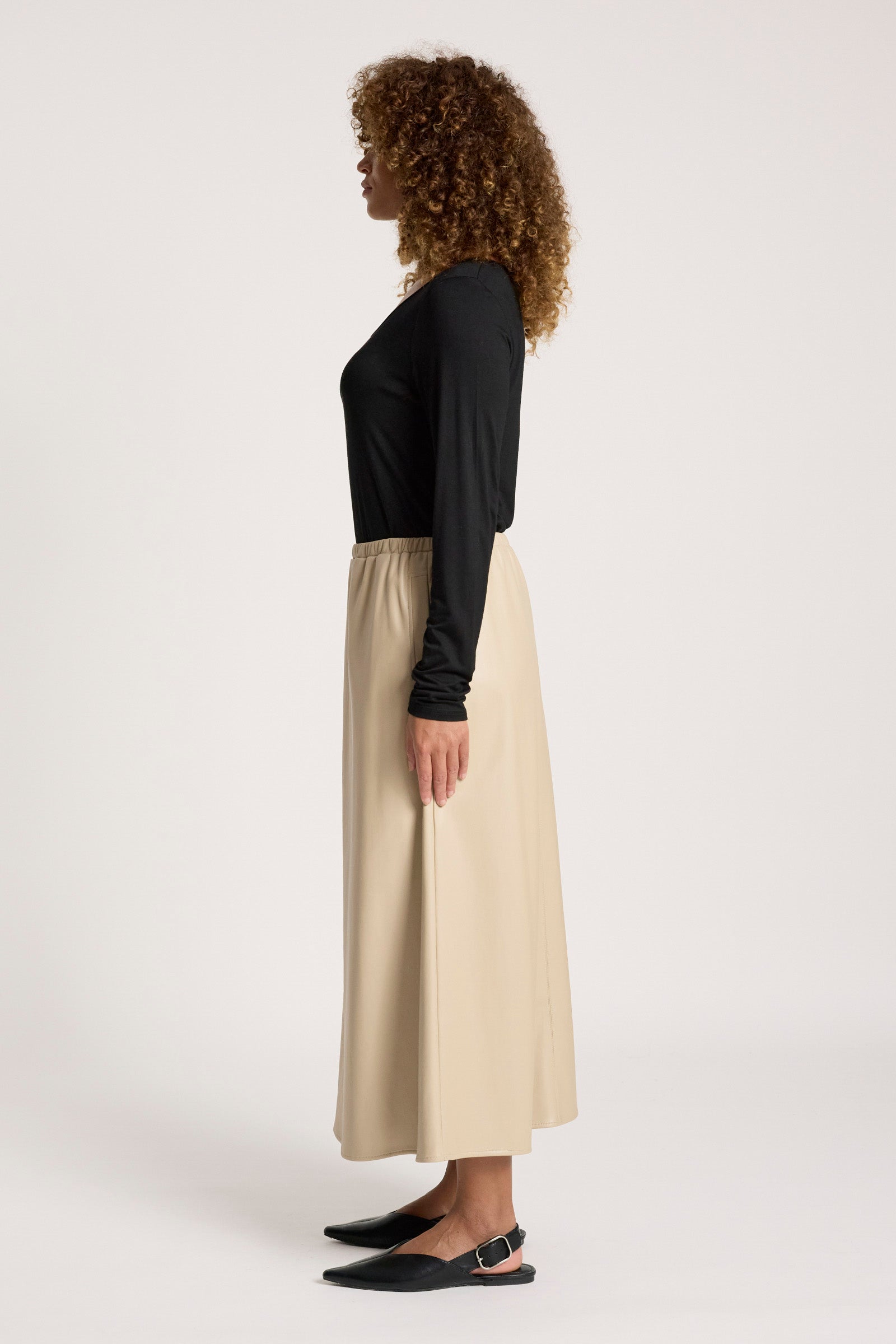 Image of Woman wearing a black top and Eb & Ive beige skirt on a white background