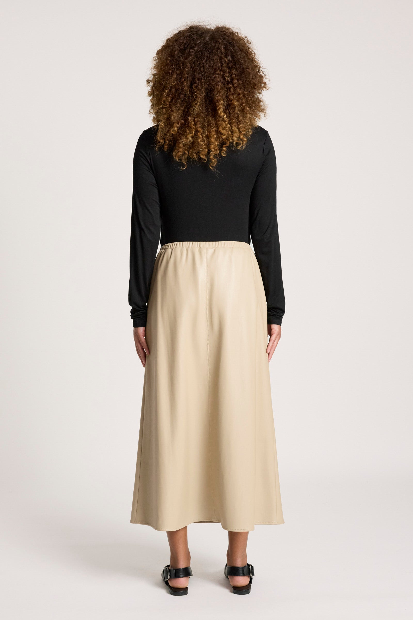 Person wearing a black top and Eb & Ive beige skirt on a white background