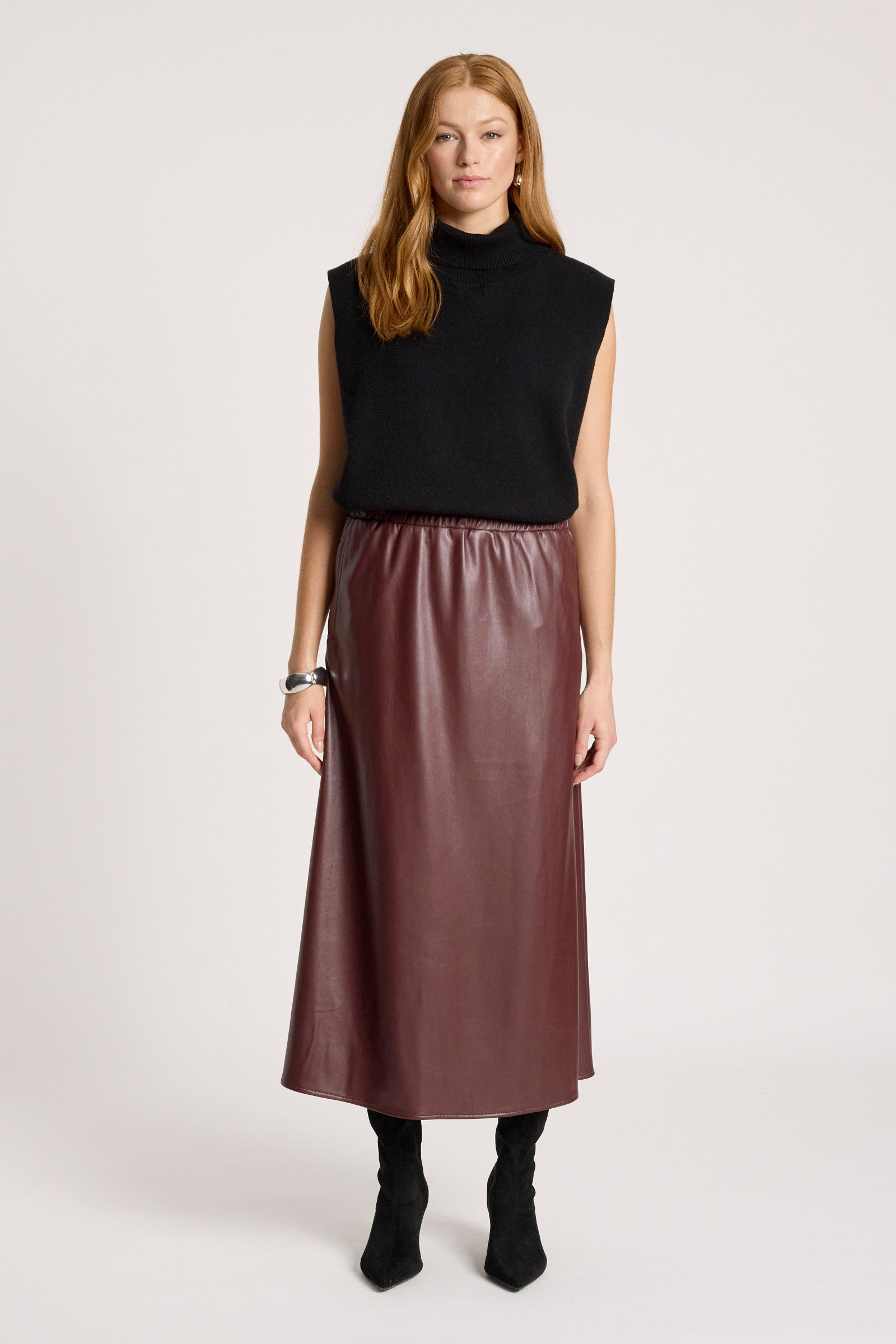 Image of Woman wearing a black sleeveless top and Eb & Ive brown leather skirt on a white background